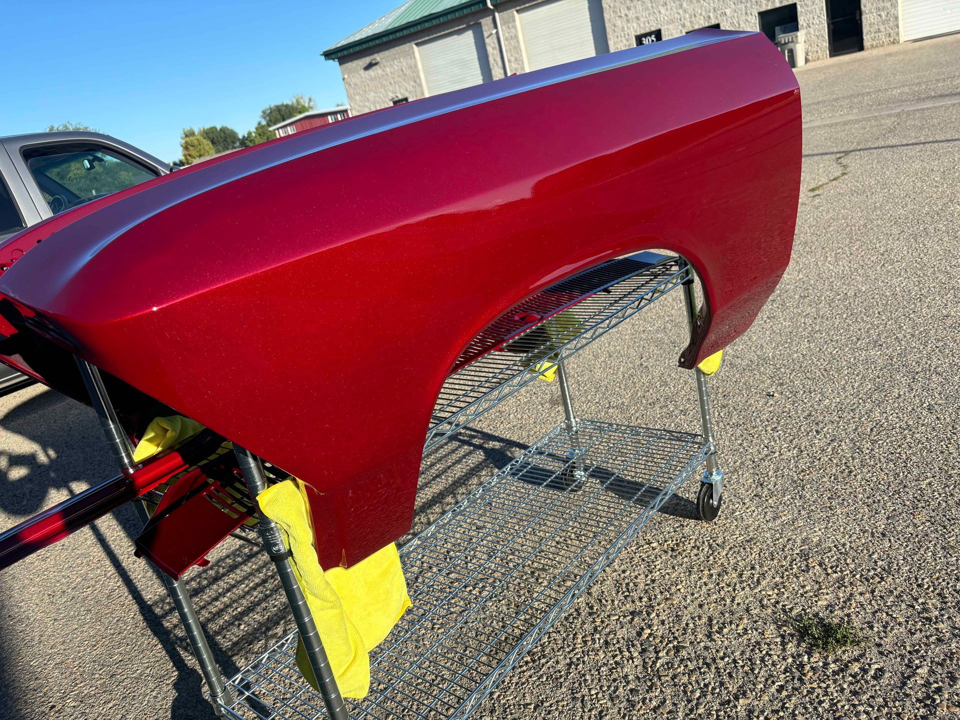 Red car fender on a stand outdoors, with yellow masking tape visible underneath.