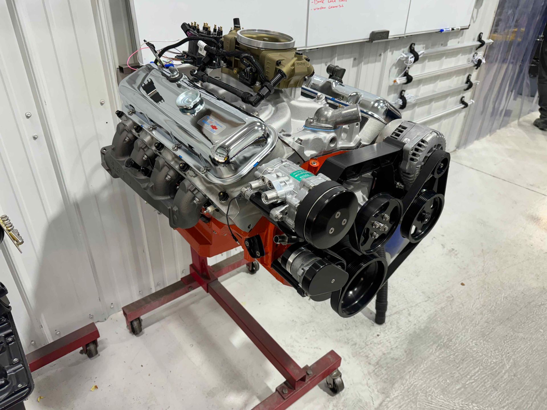V8 engine mounted on a red stand in a workshop with white walls and floor
