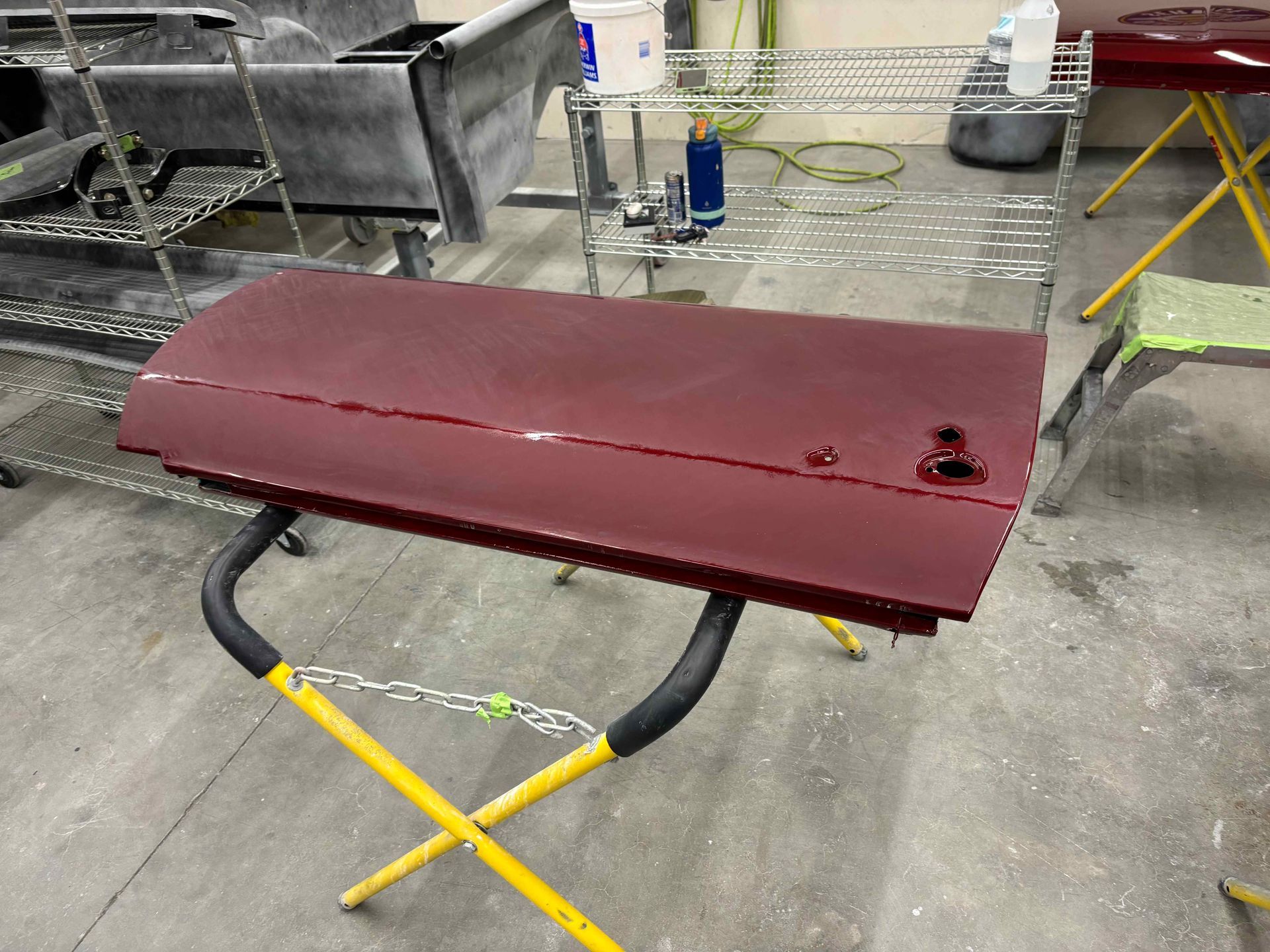 Maroon rectangular workbench on sawhorse-style legs in a workshop floor area