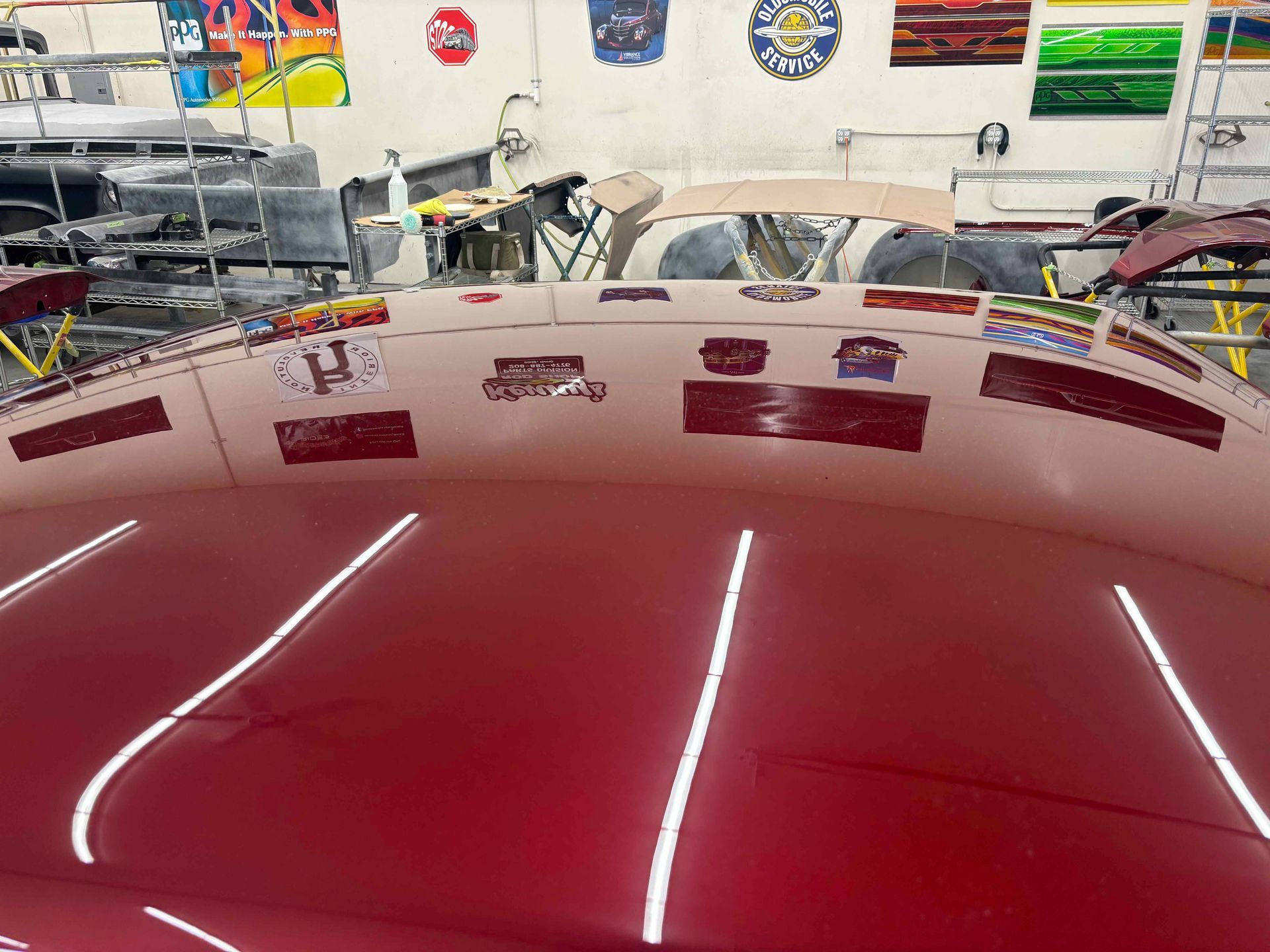 Shiny red car hood in a garage with overhead lights reflecting off the surface