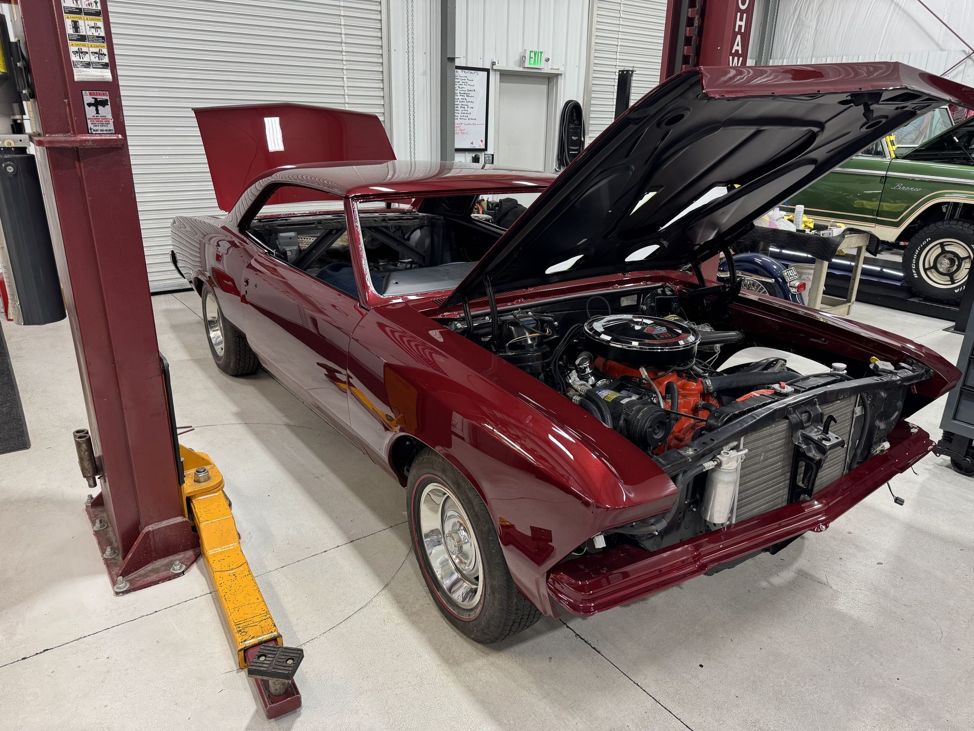 Maroon classic car with hood open in an auto shop, exposing the engine area