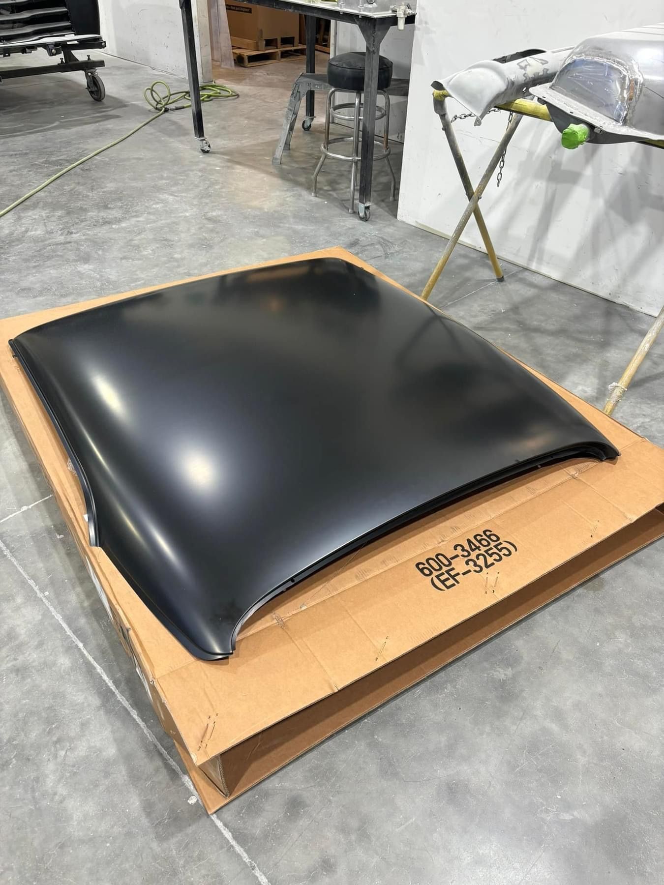 Black curved panel on a cardboard box in a workshop setting