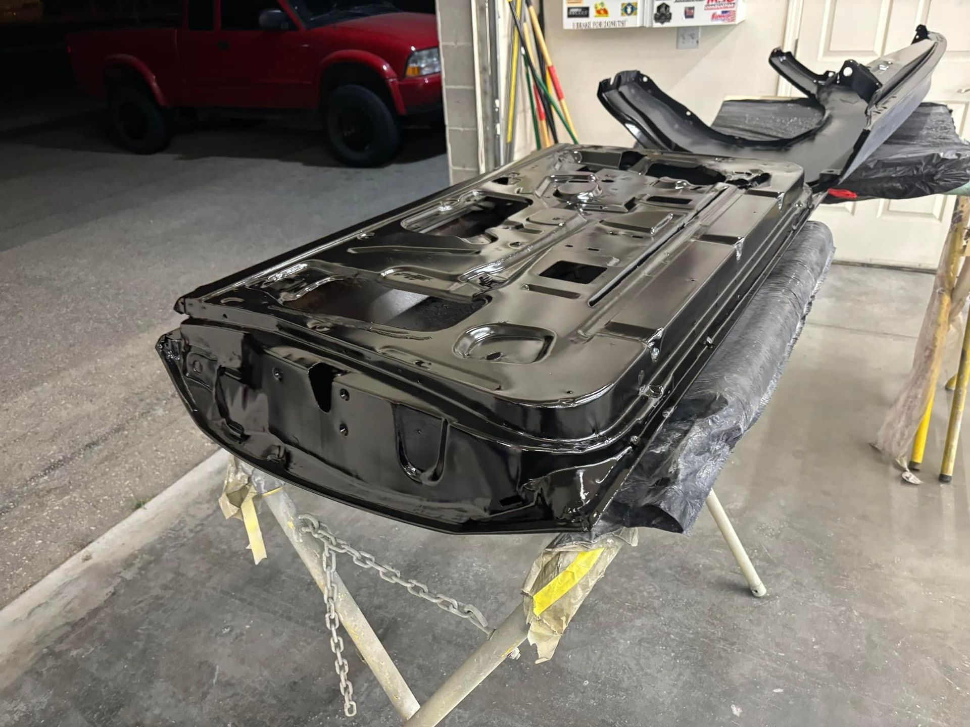 Black car body shell on a stand in a workshop, with the interior removed and exposed.