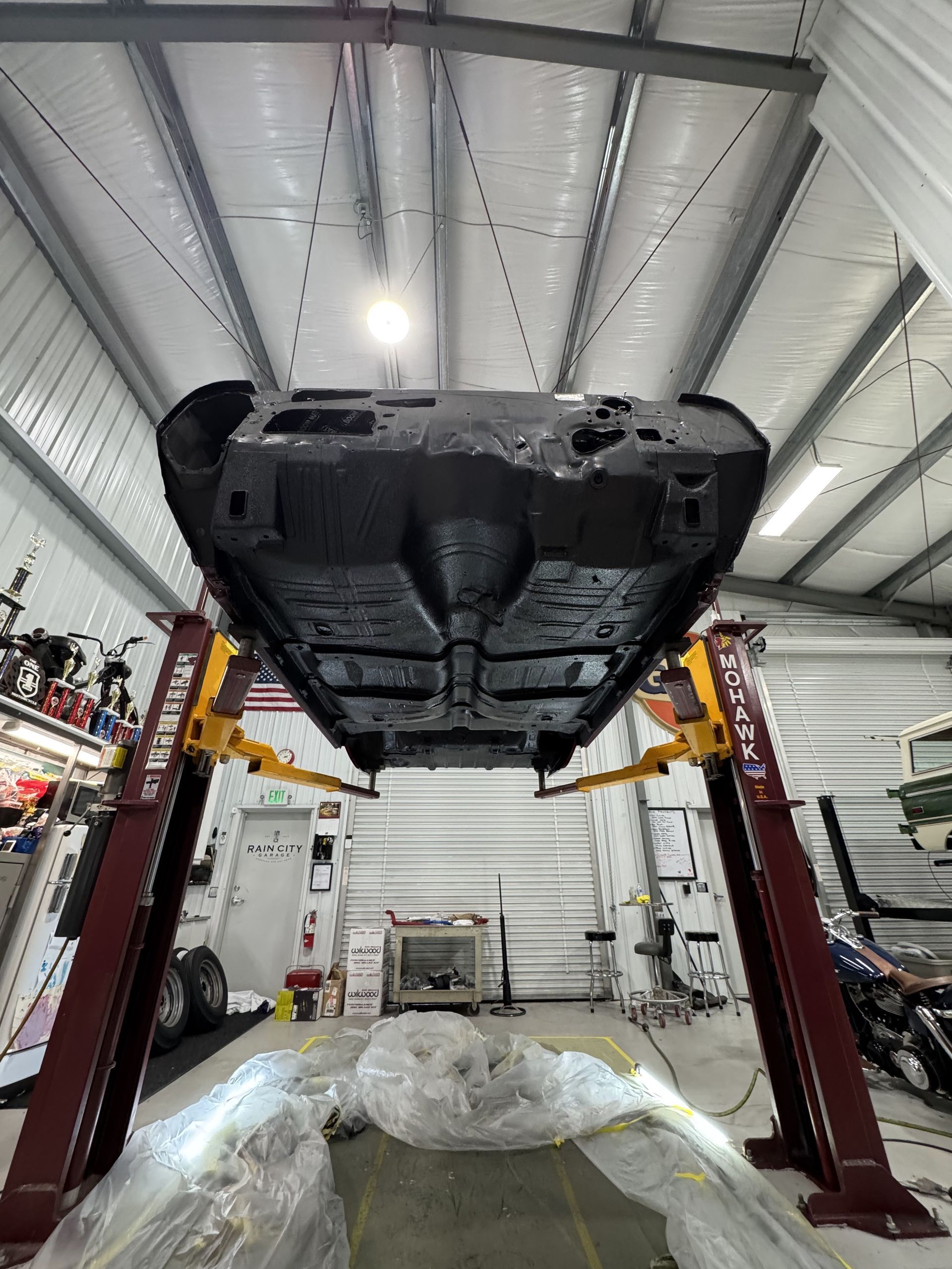 Underside of a car lifted on a red automotive hoist inside a garage workshop