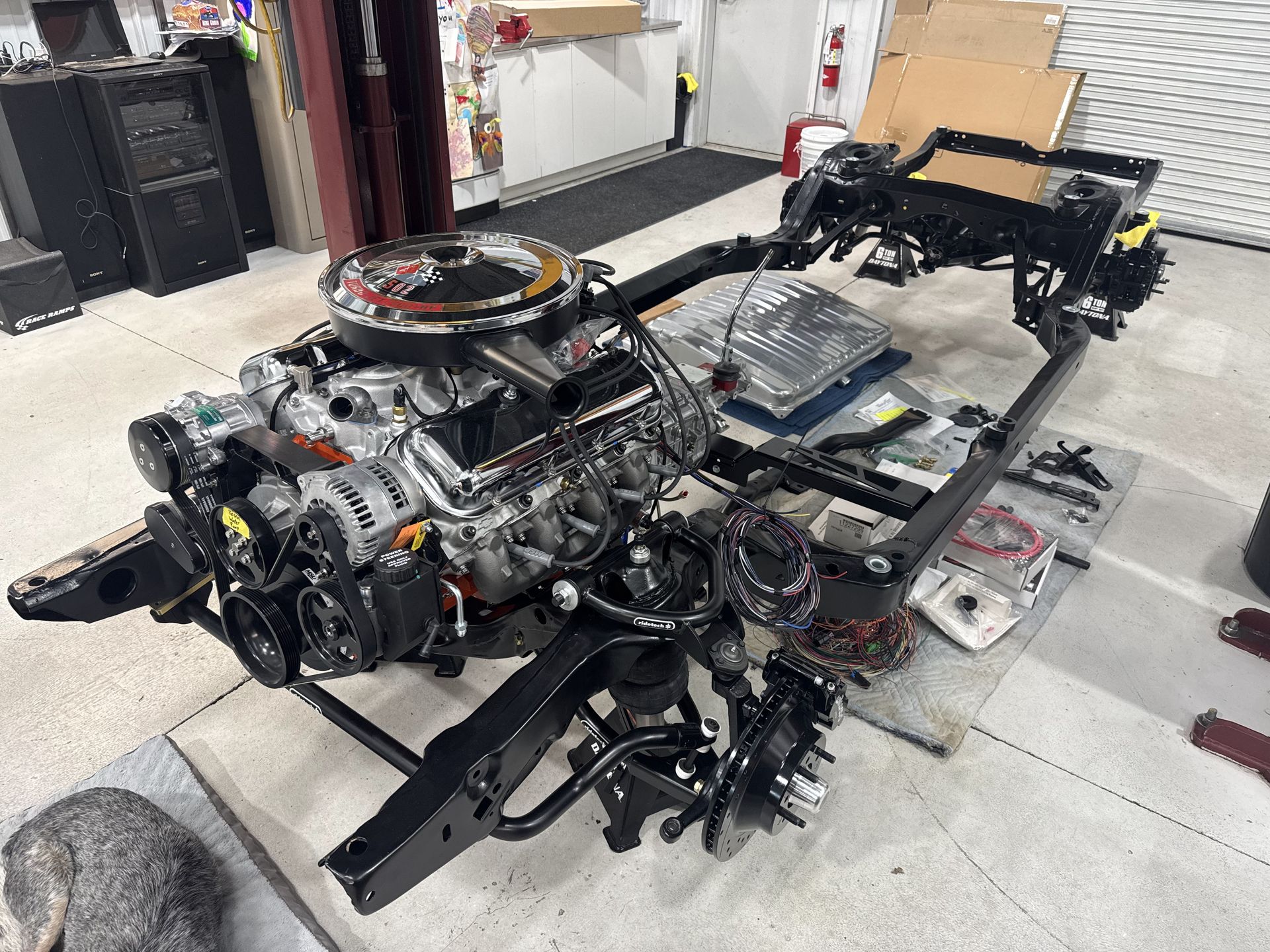 Scattered car chassis and mechanical parts in a workshop, with exposed engine and frame components.