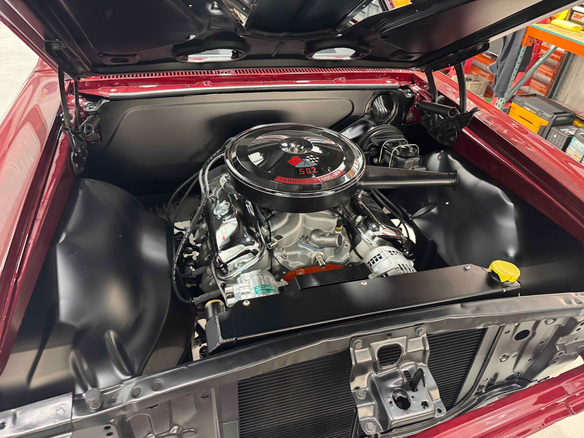 Close-up of a car engine bay with a chrome engine and black components under an open hood.