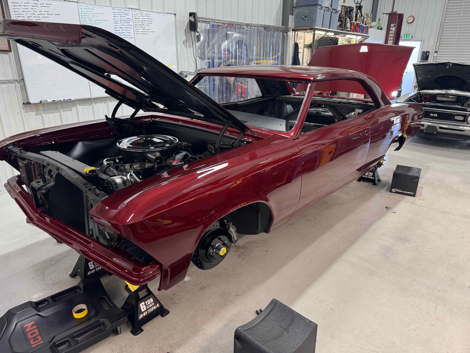 Maroon classic car body in an auto shop, hood and trunk open during restoration