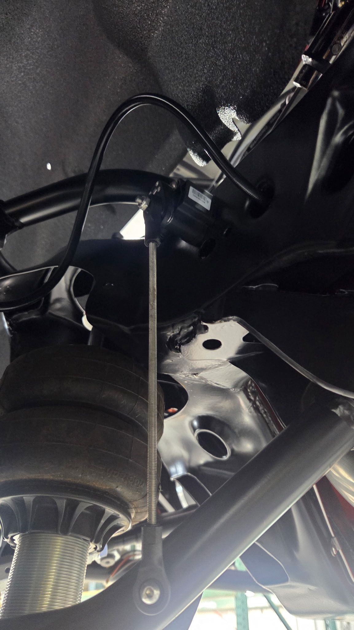 Undercarriage of a vehicle with suspension, wheel, and exposed wiring close-up