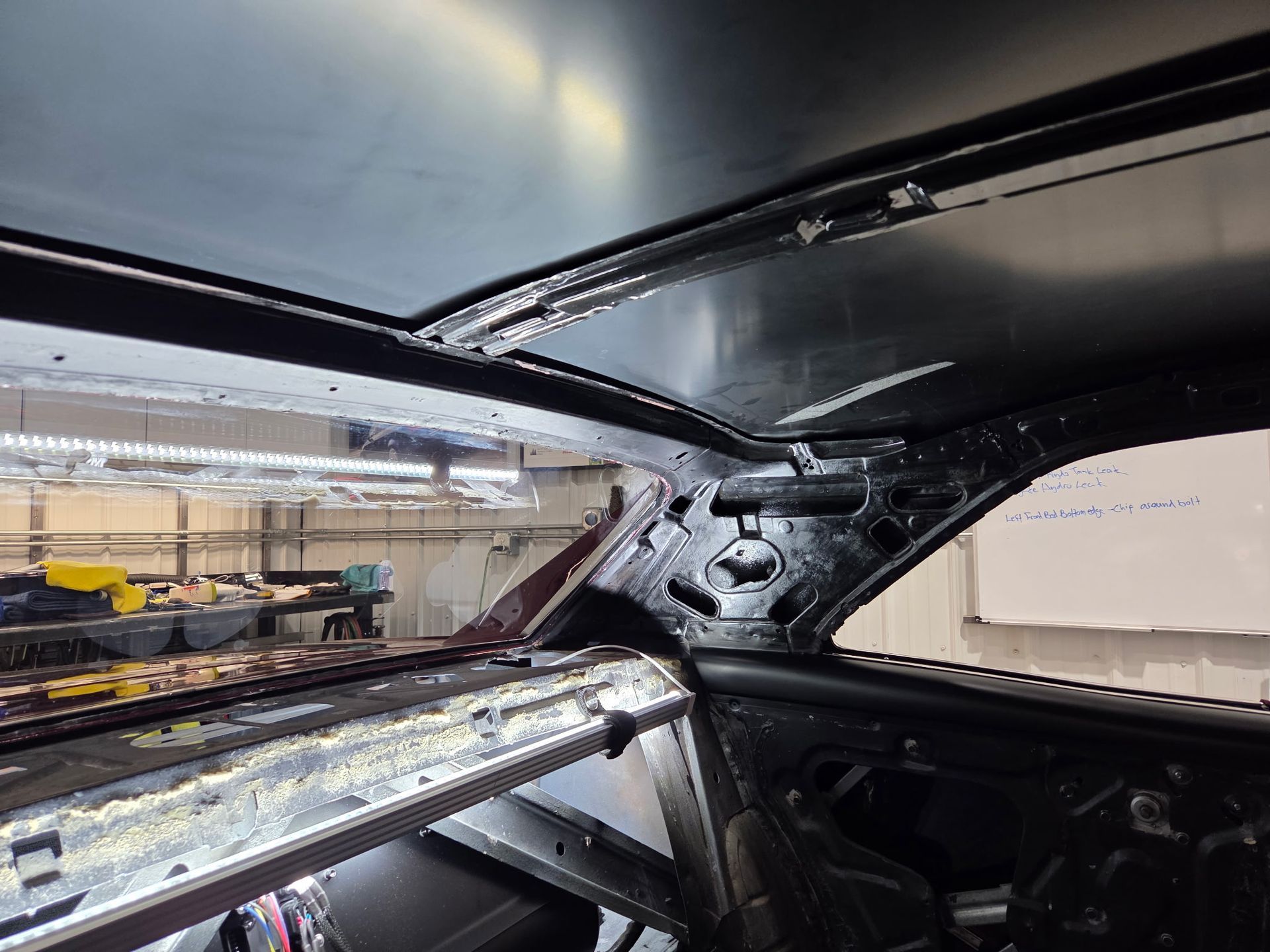 Interior of a car frame under construction, with exposed metal panels in a workshop.