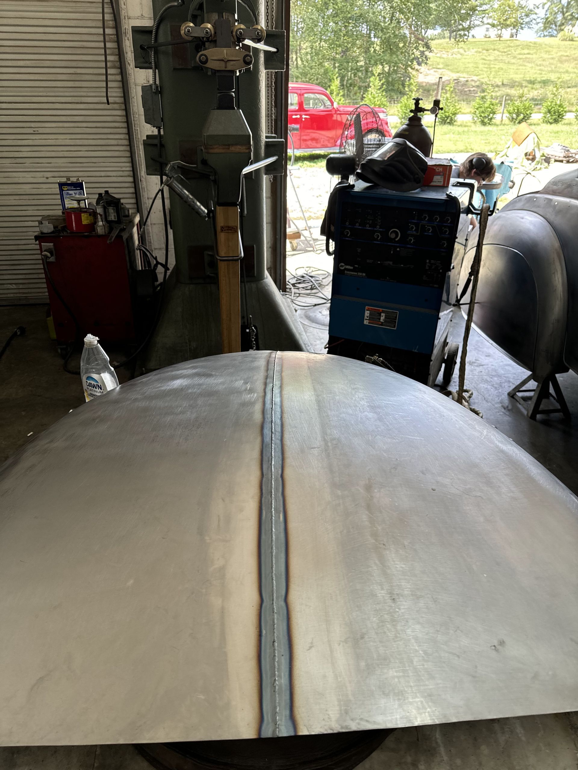 Worn boat hull in a garage, with tools and equipment in the background.