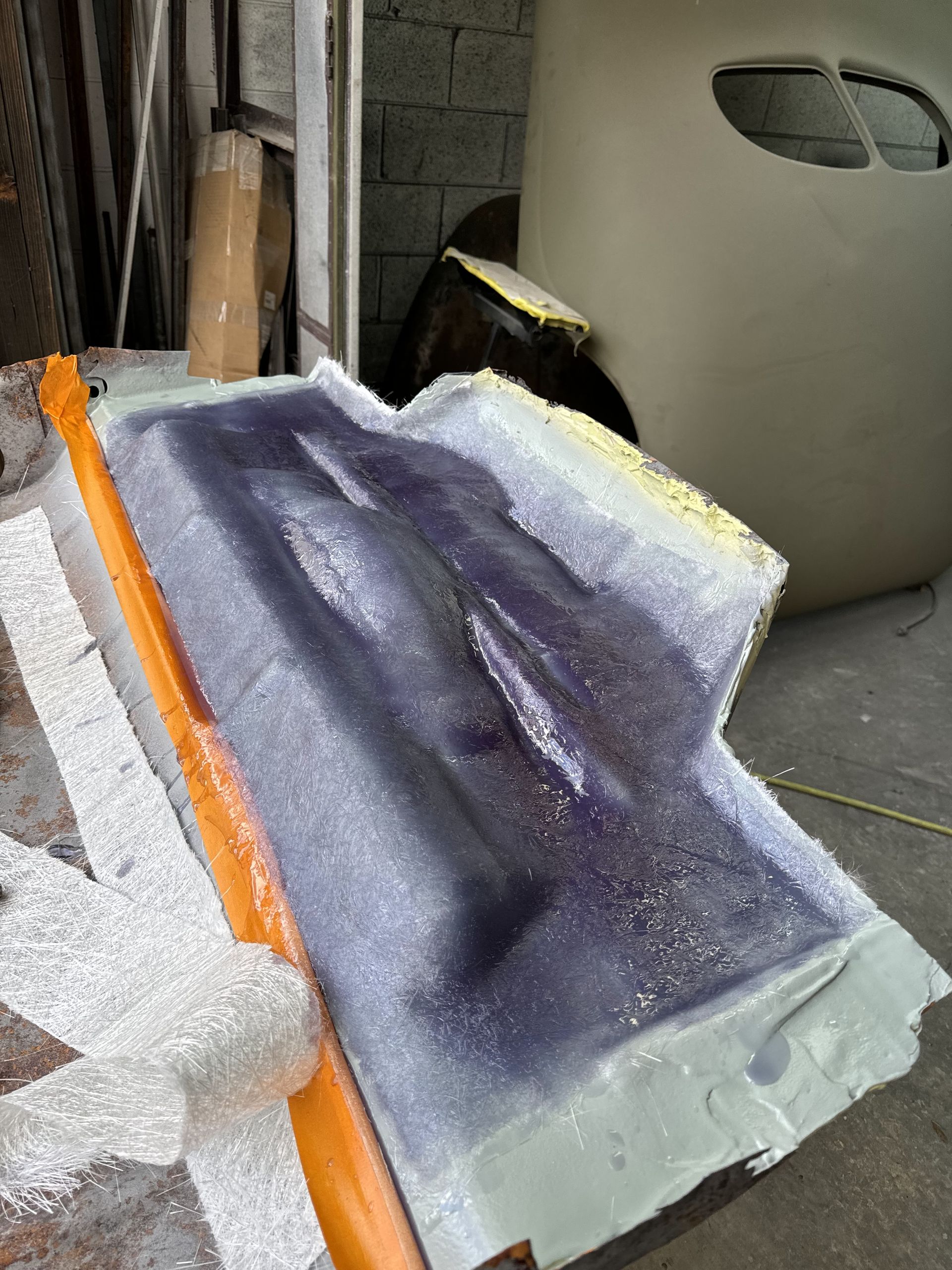 Purple foam or fabric piece with orange edge and white base leaning in a workshop setting