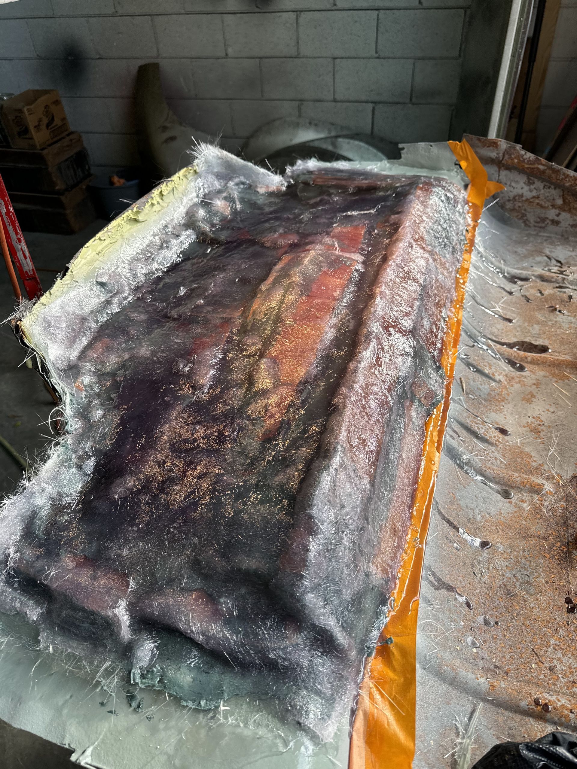 Melted black and orange tarp-like material spread over a workbench in a garage or workshop.