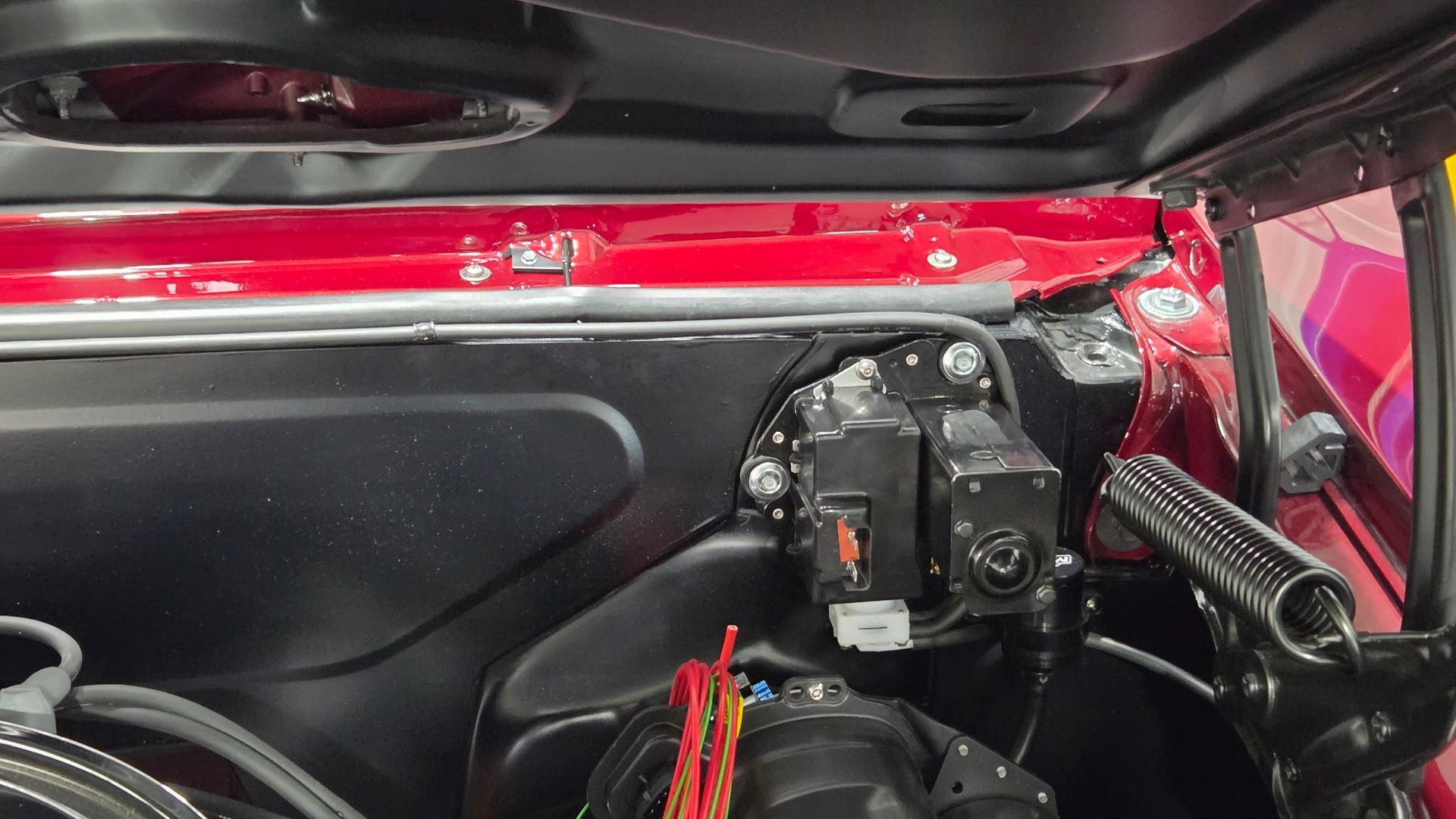 Car door interior with exposed black components and a red metal frame visible at the top and side