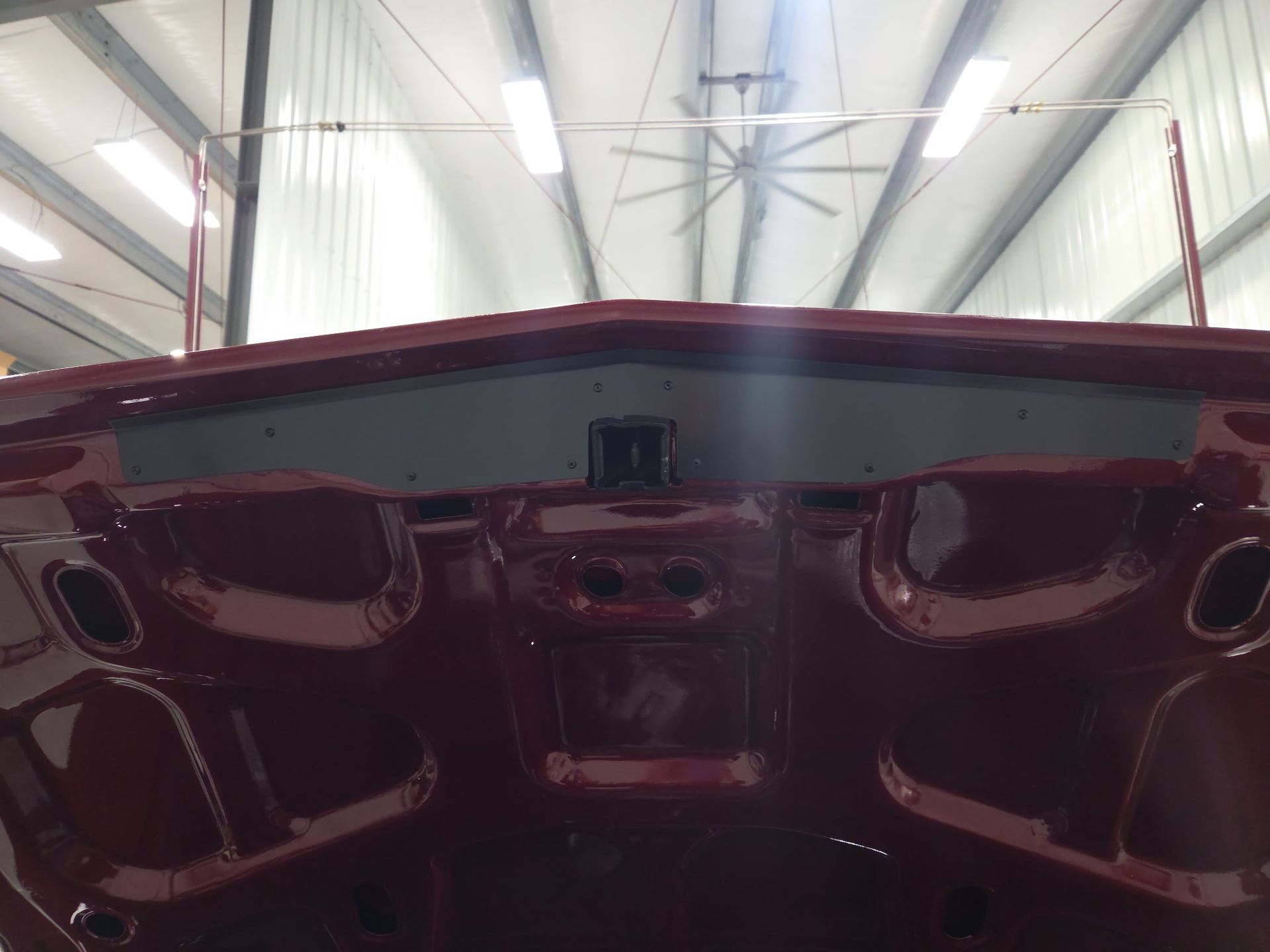 Open car trunk with black interior panels and red exterior in a workshop garage