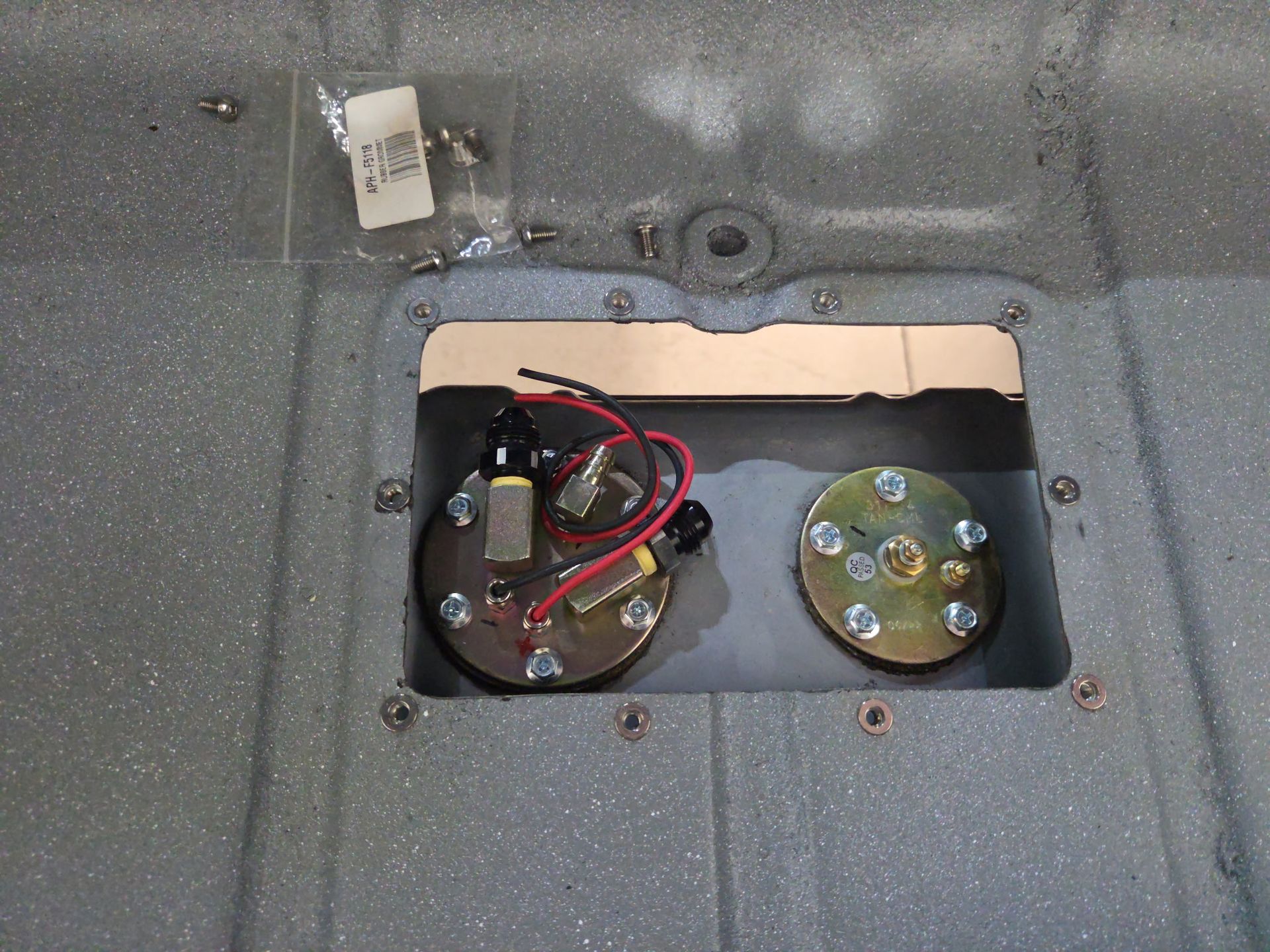 Open panel in a gray appliance interior, showing two circular components with wires and connectors.