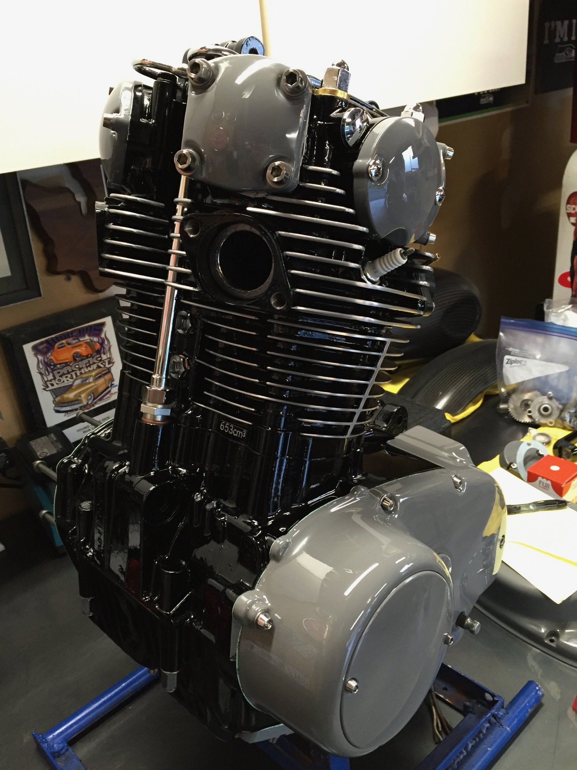Black motorcycle engine on a workbench, with gray covers and exposed fins.