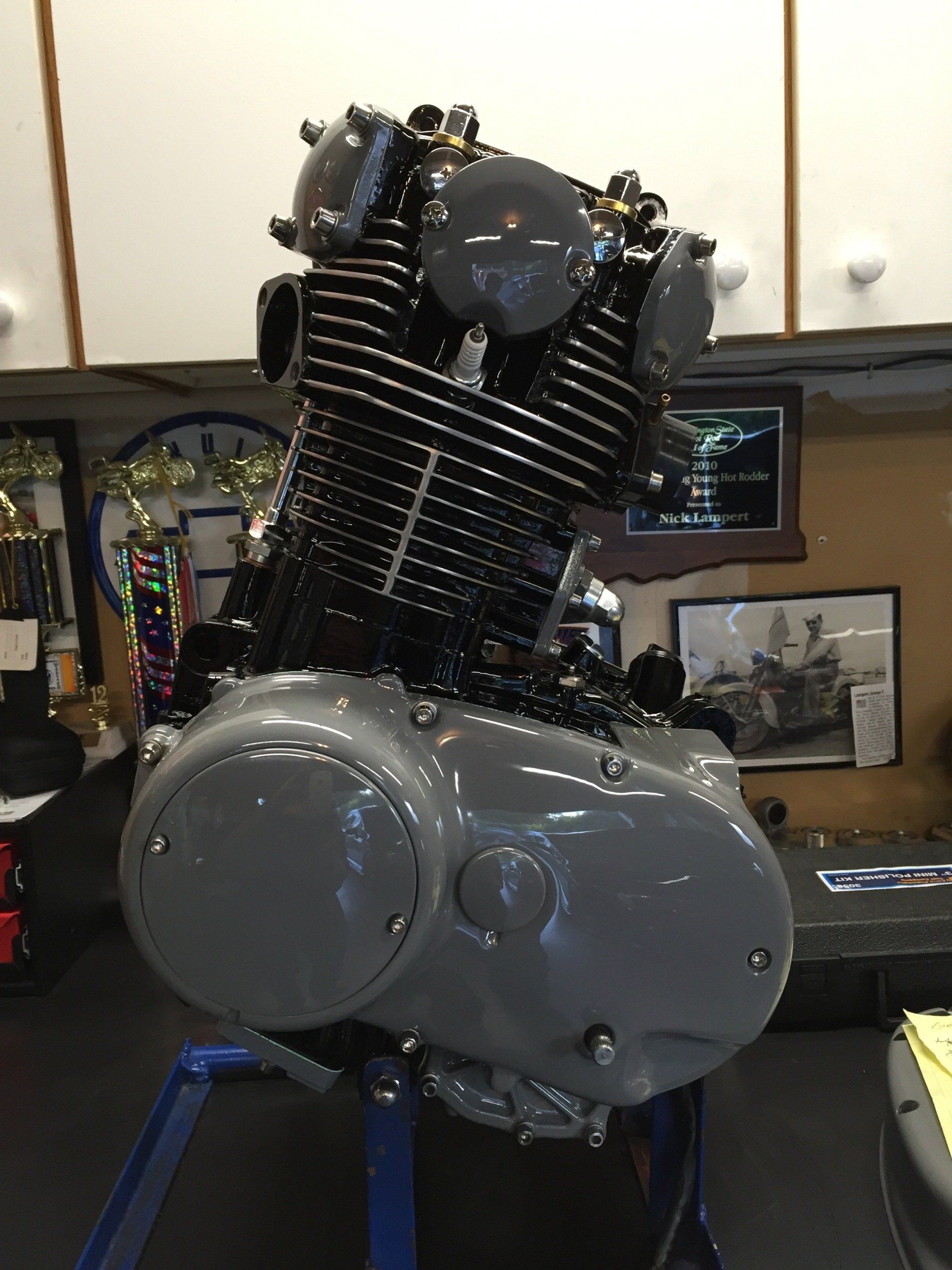 Close-up of a V-twin motorcycle engine with black fins and chrome covers on display indoors