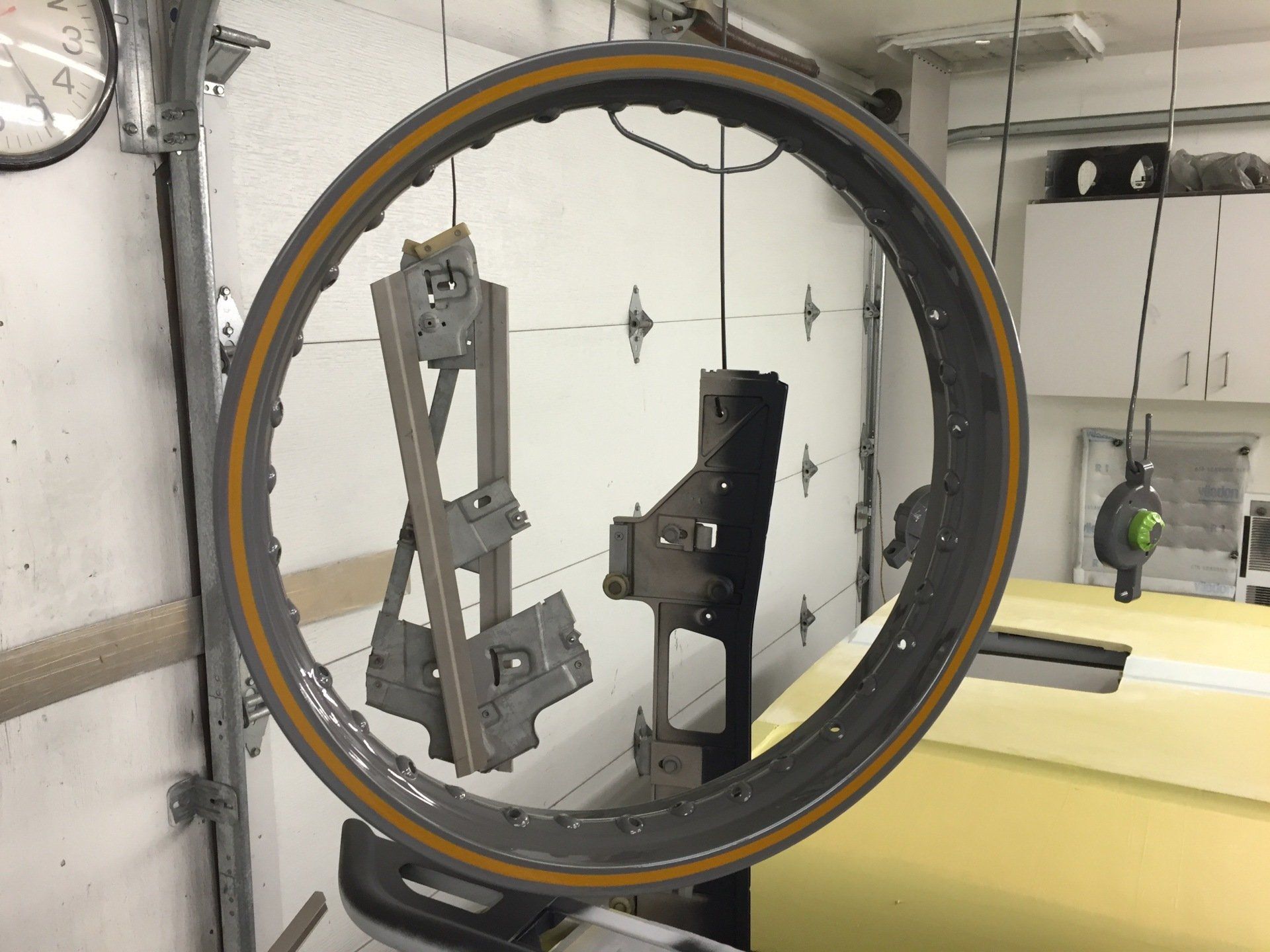 Large circular metal ring in an industrial workshop, with machinery mounted inside and cabinets in the background