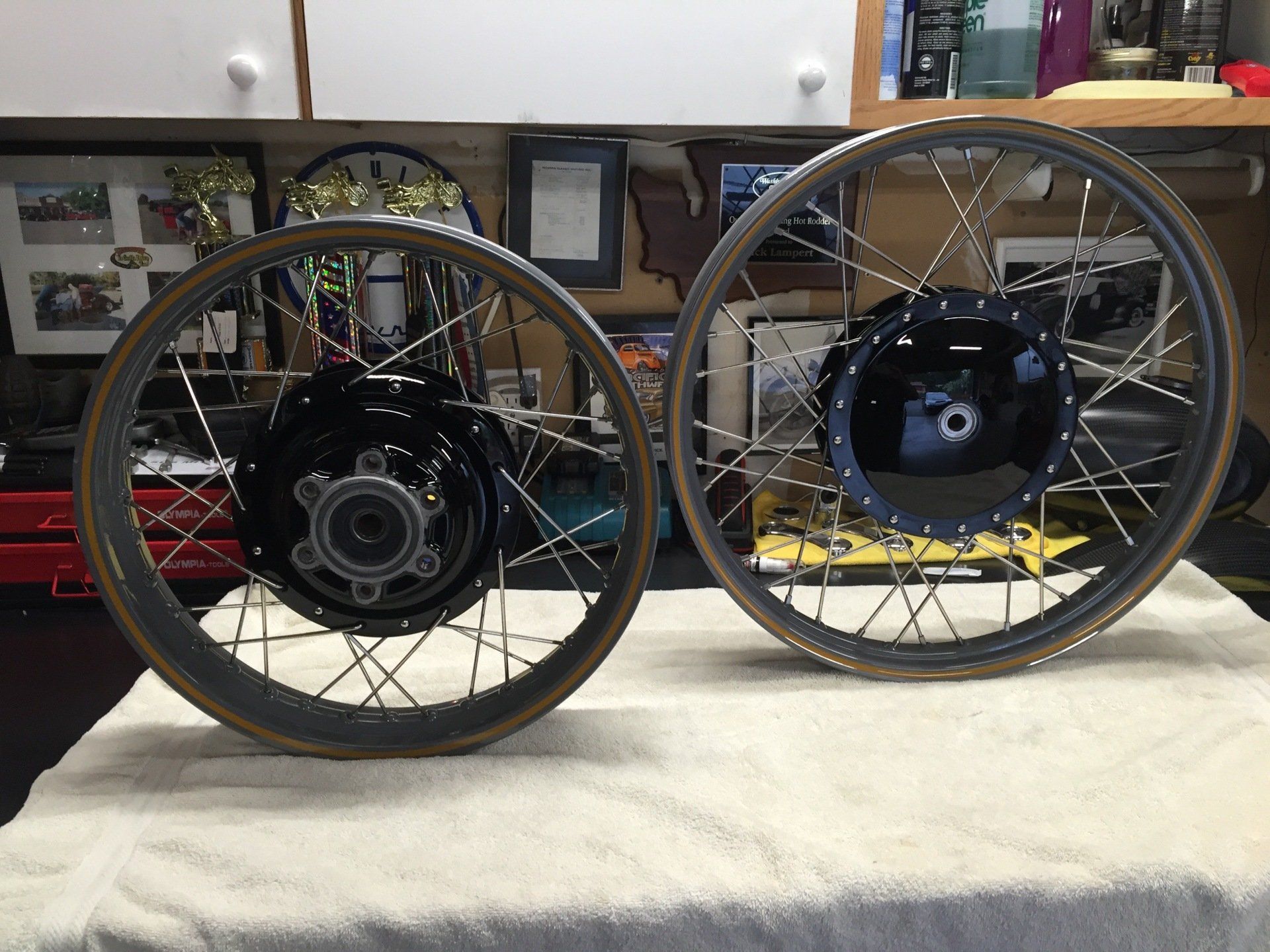 Two bicycle wheels with hubs mounted side by side on a workbench.