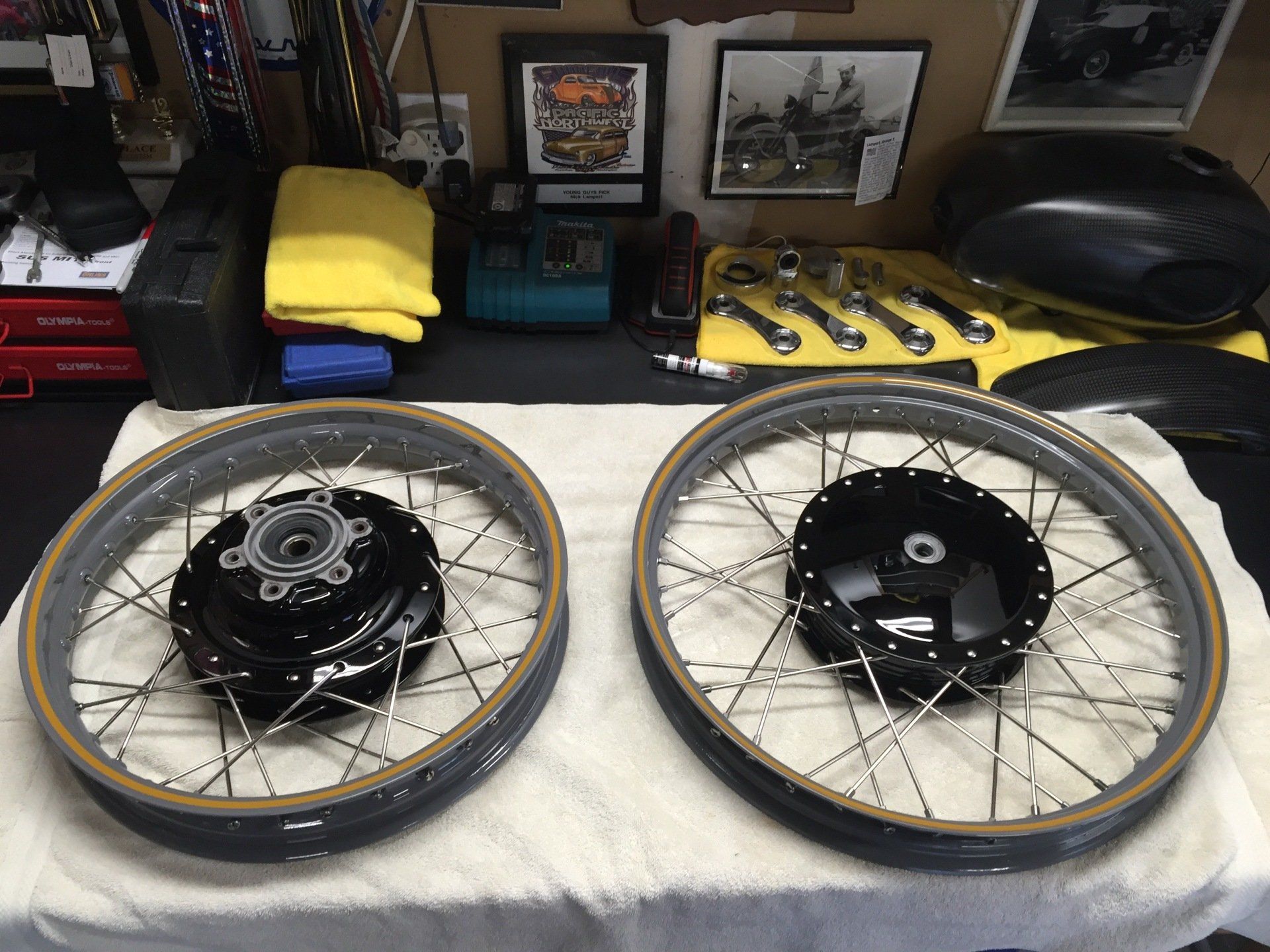 Two spoked bicycle wheels on a table, one with a black hub assembly and one with a black hub center.