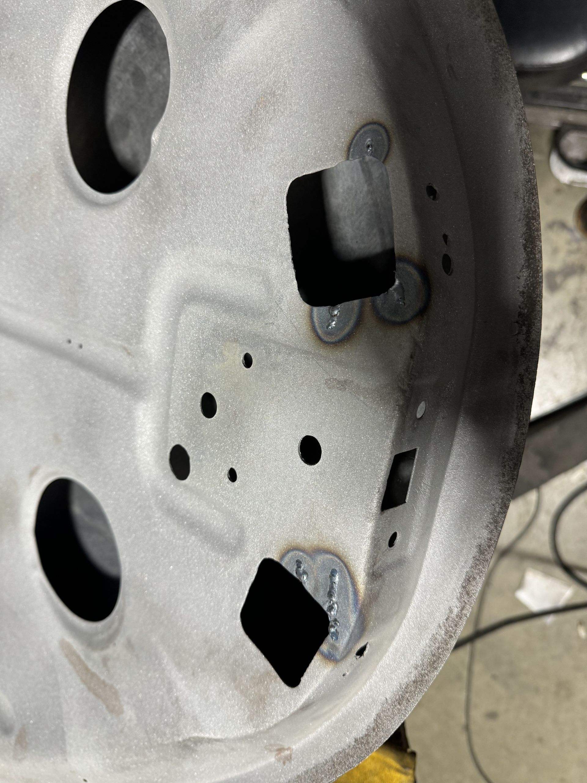 Close-up of a silver metal panel with round holes and black cutouts inside a machine or device