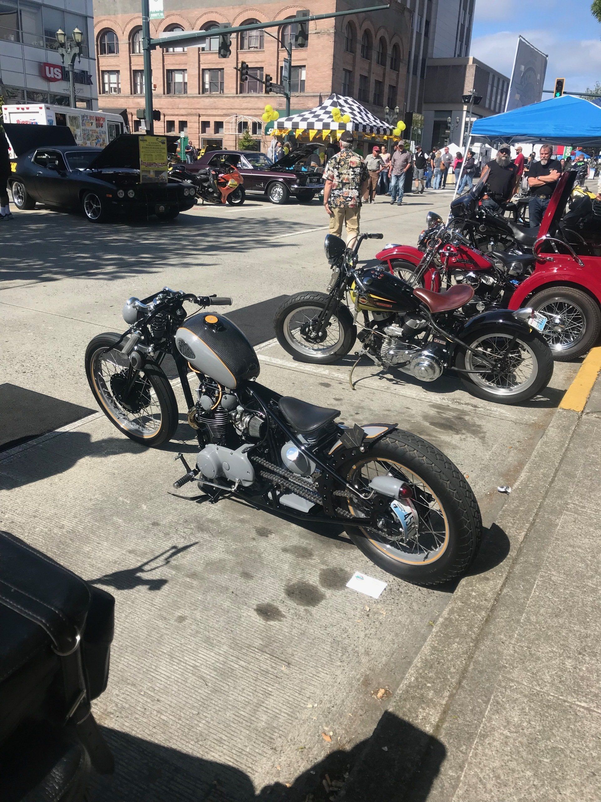 Several custom motorcycles parked on a city street at an outdoor event