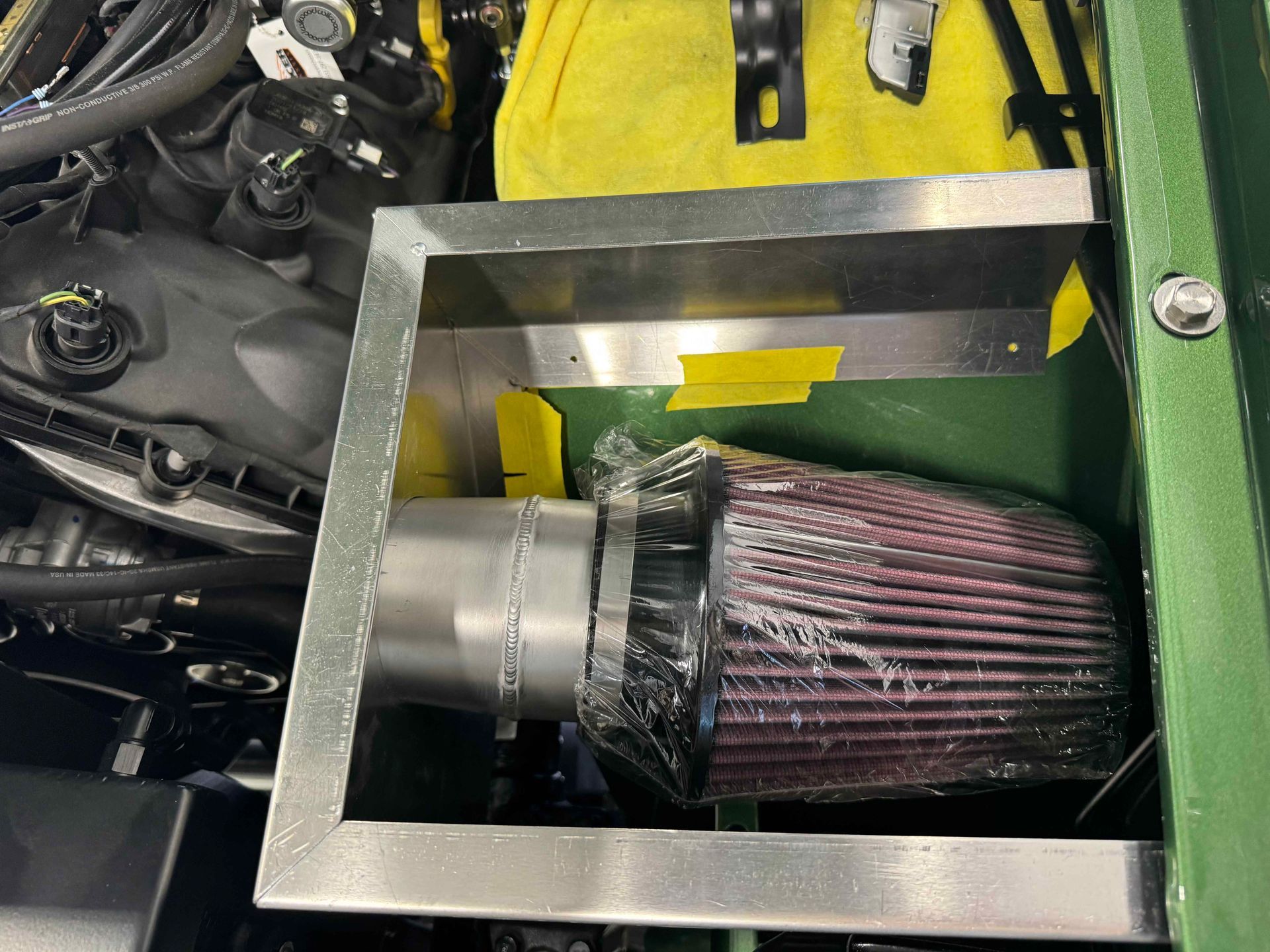 Close-up of a pink cone air filter installed in a metal engine bay opening