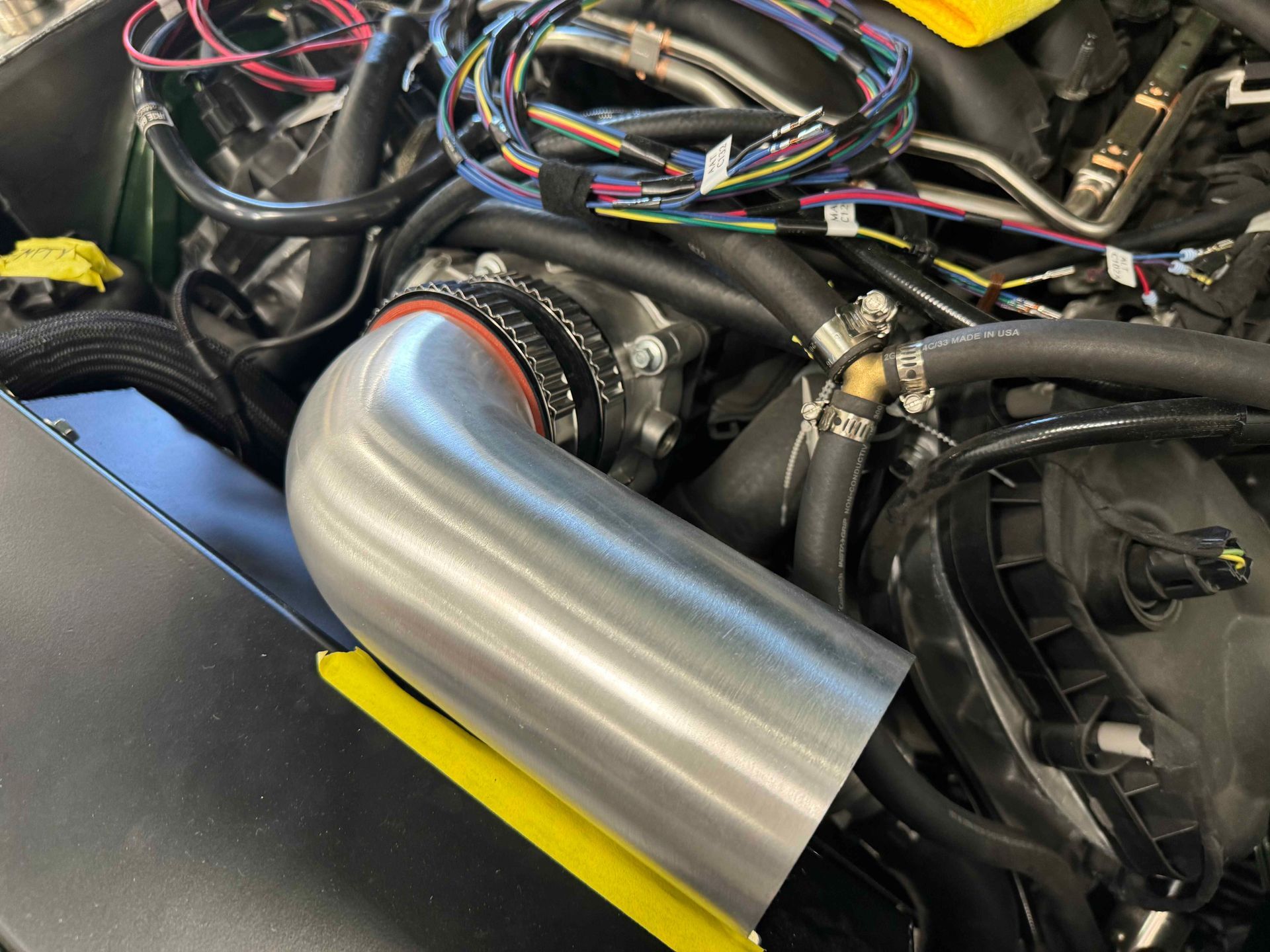 Close-up of a car engine bay with a large silver intake pipe and visible wiring.