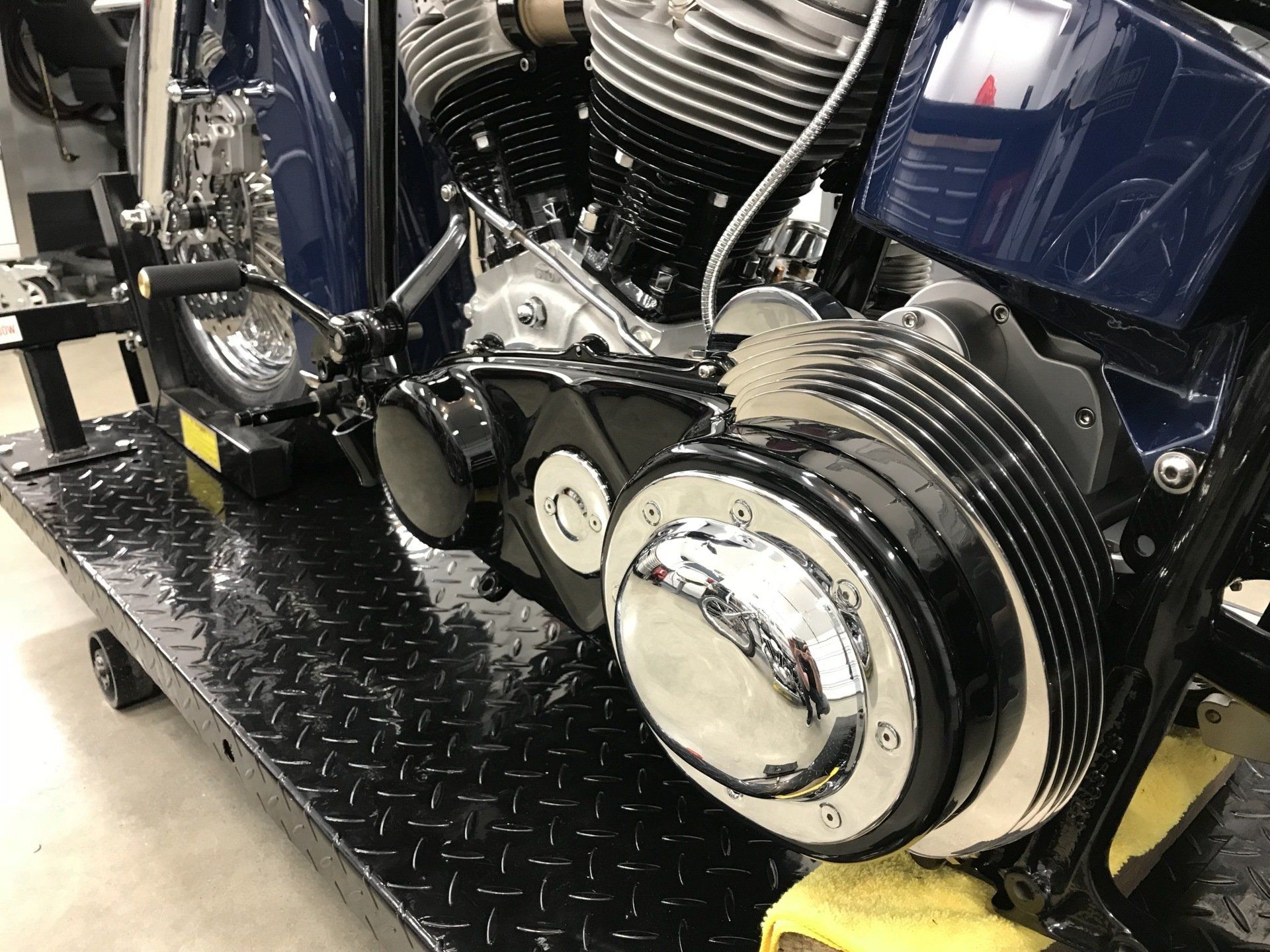 Close-up of a chrome motorcycle engine with black and blue bodywork on a display platform