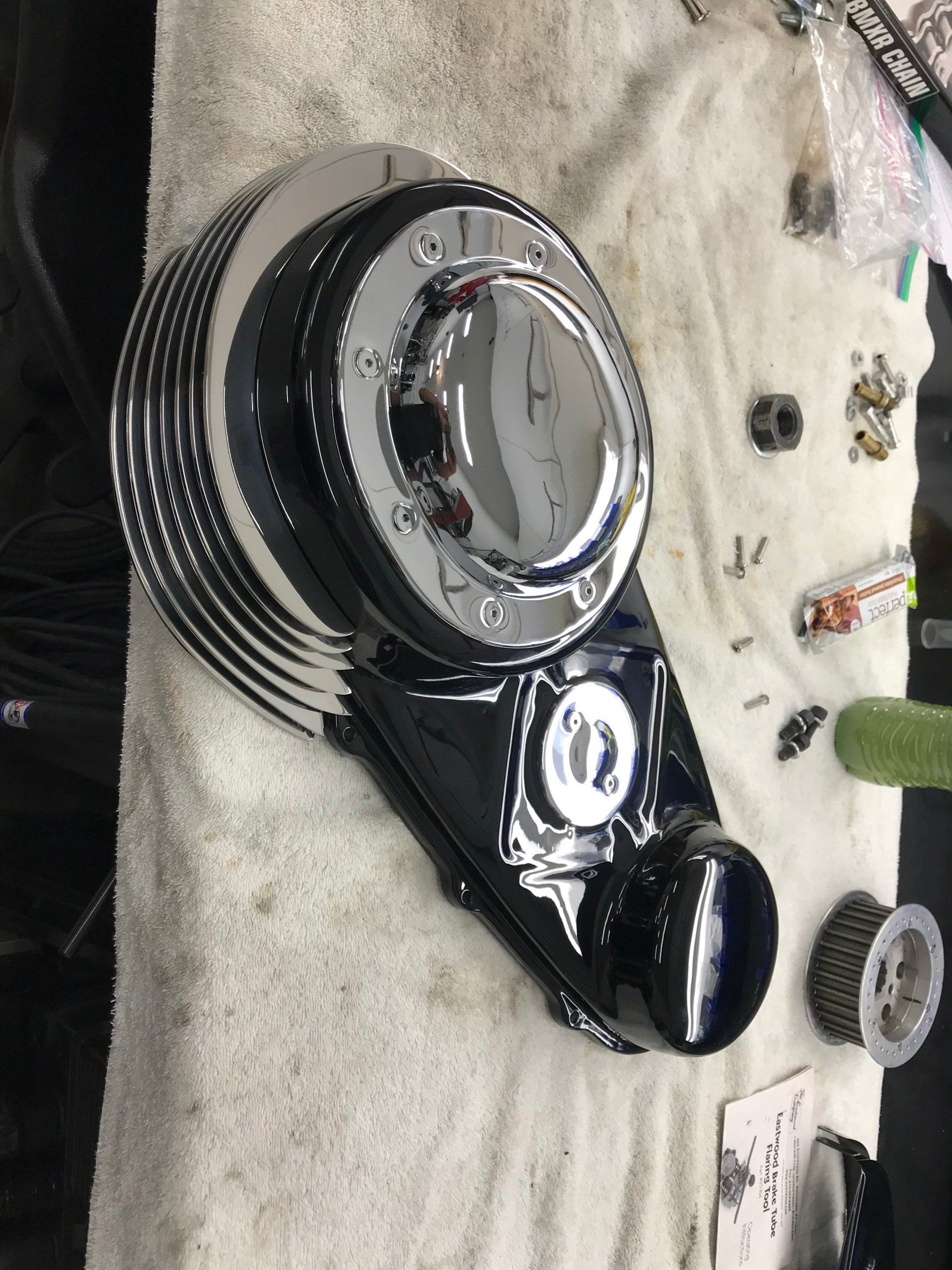 Black engine cover assembly on a workbench with tools and parts nearby
