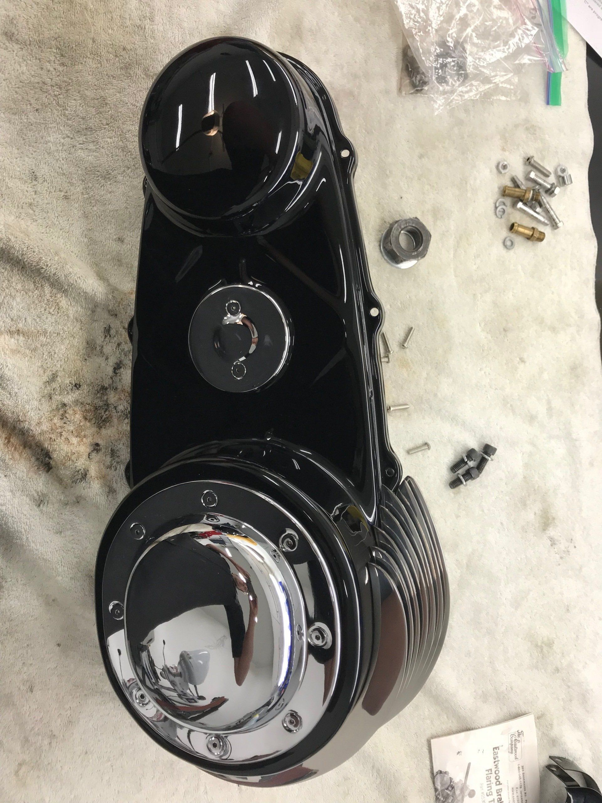 Black glossy scooter/moped throttle housing with chrome accents on a workbench, with screws nearby