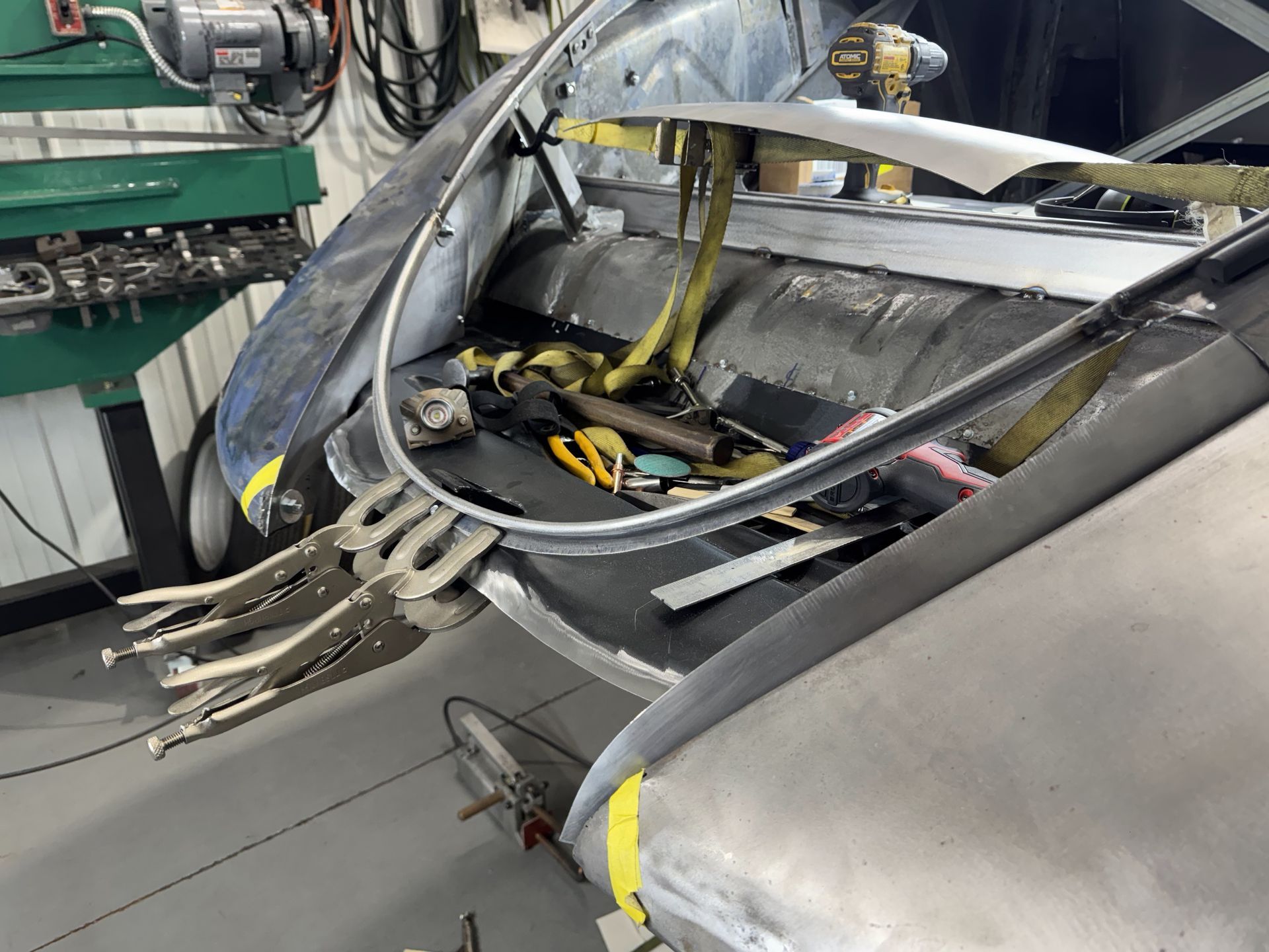 Damaged gray aircraft fuselage with exposed interior wiring and metal framework in a workshop