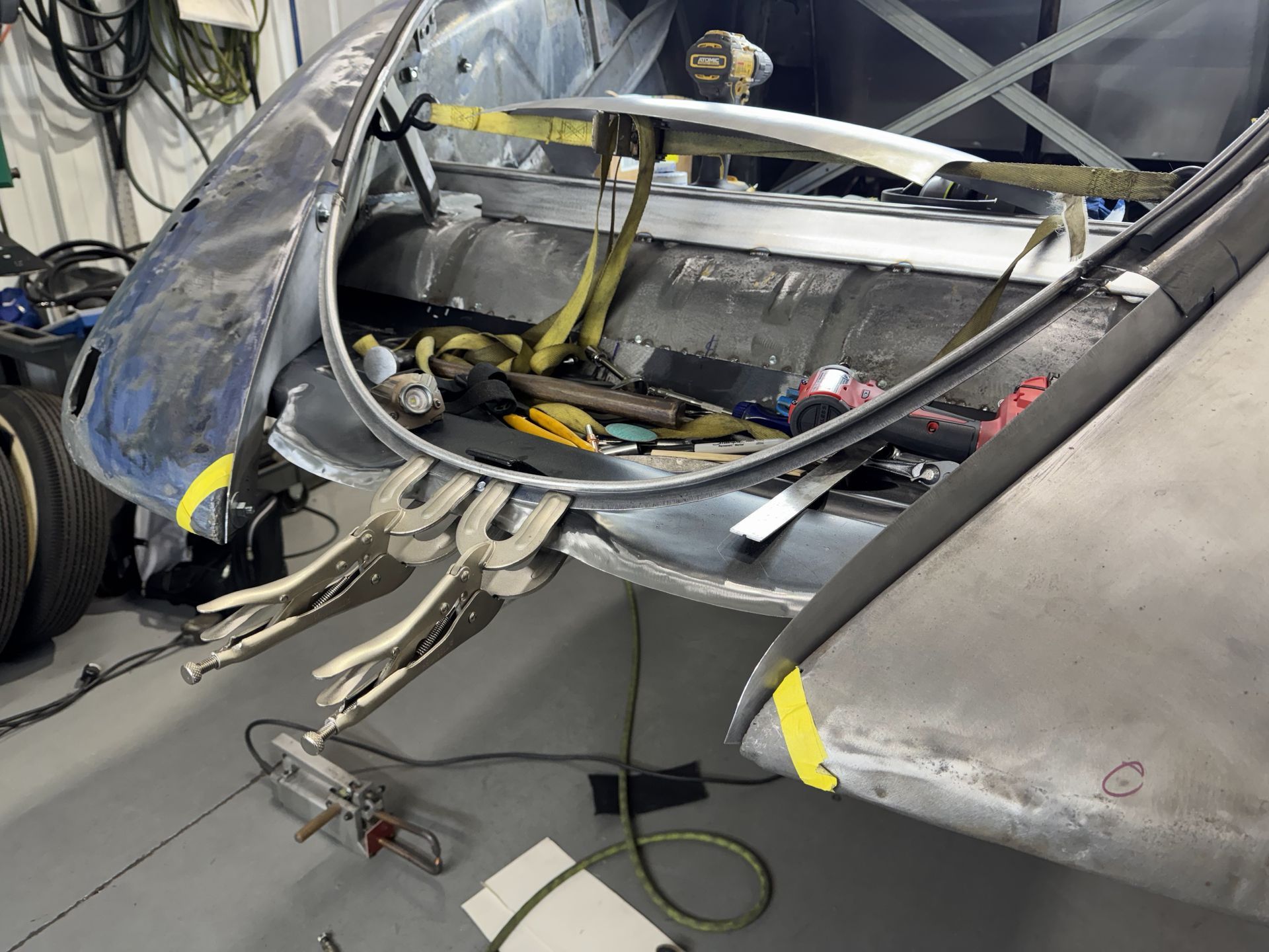 Damaged aircraft cockpit with broken canopy and exposed wiring inside a hangar