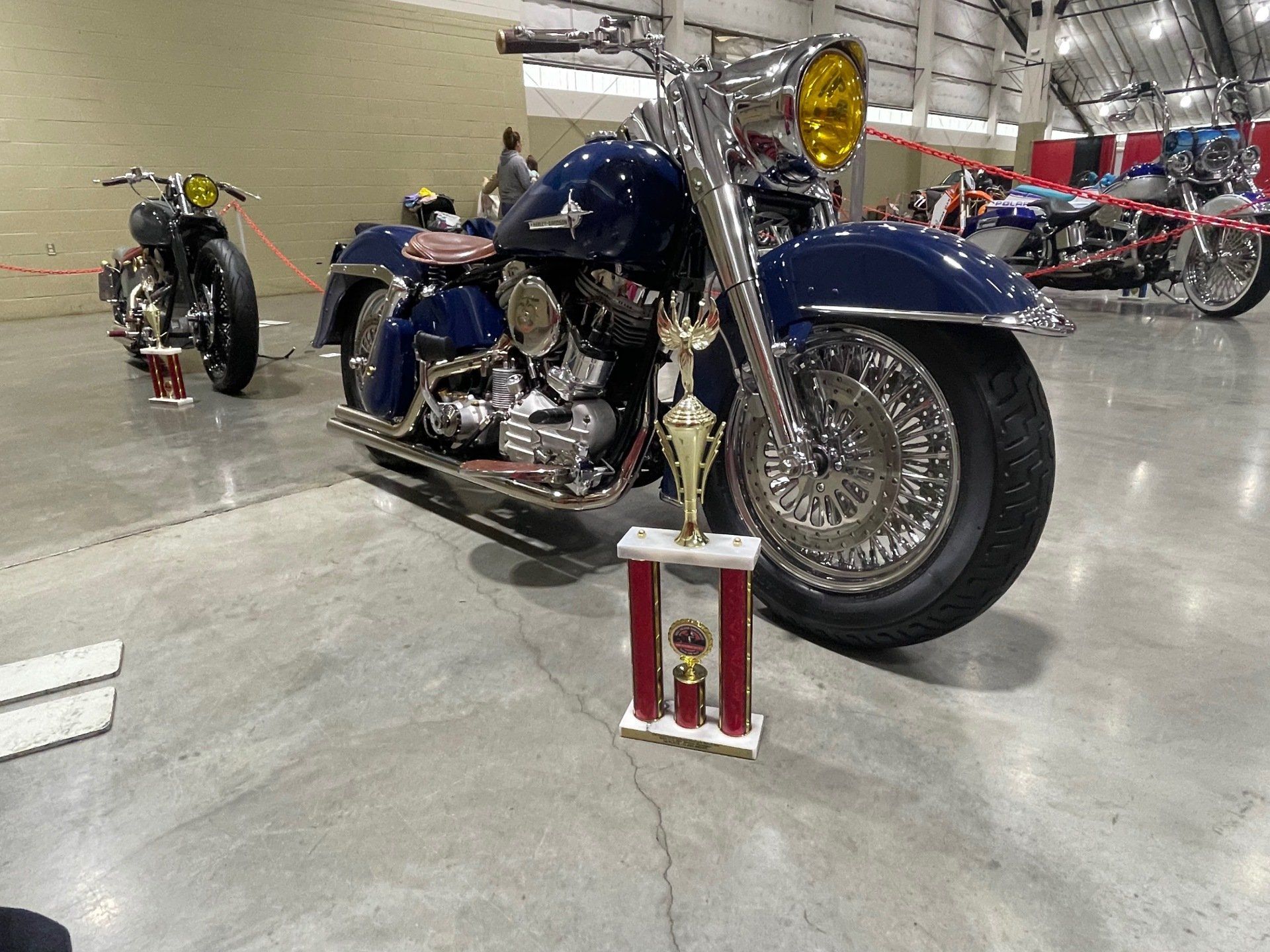 Blue custom motorcycle with a trophy displayed in an indoor showroom