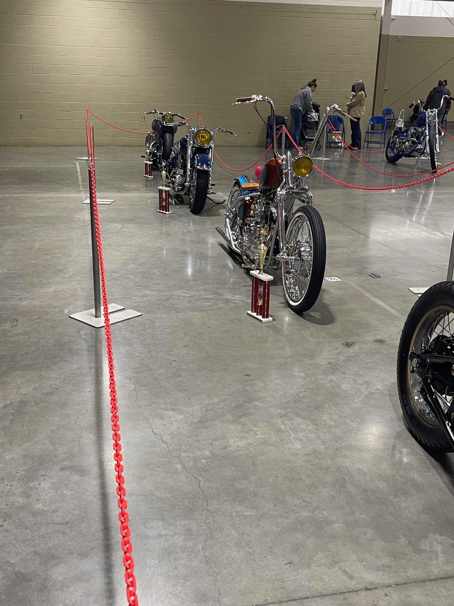 Bicycles lined up behind red tape in a concrete indoor venue.