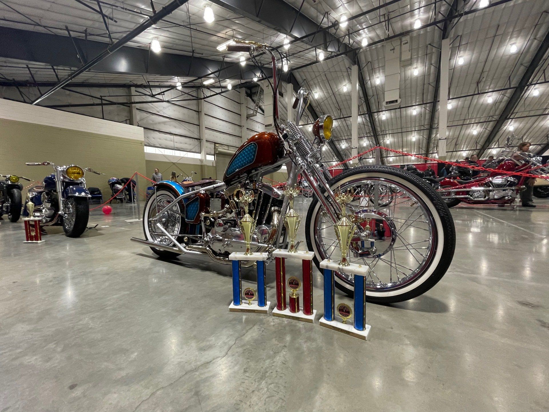 Custom lowrider-style bicycle with chrome details and trophies in a showroom indoors