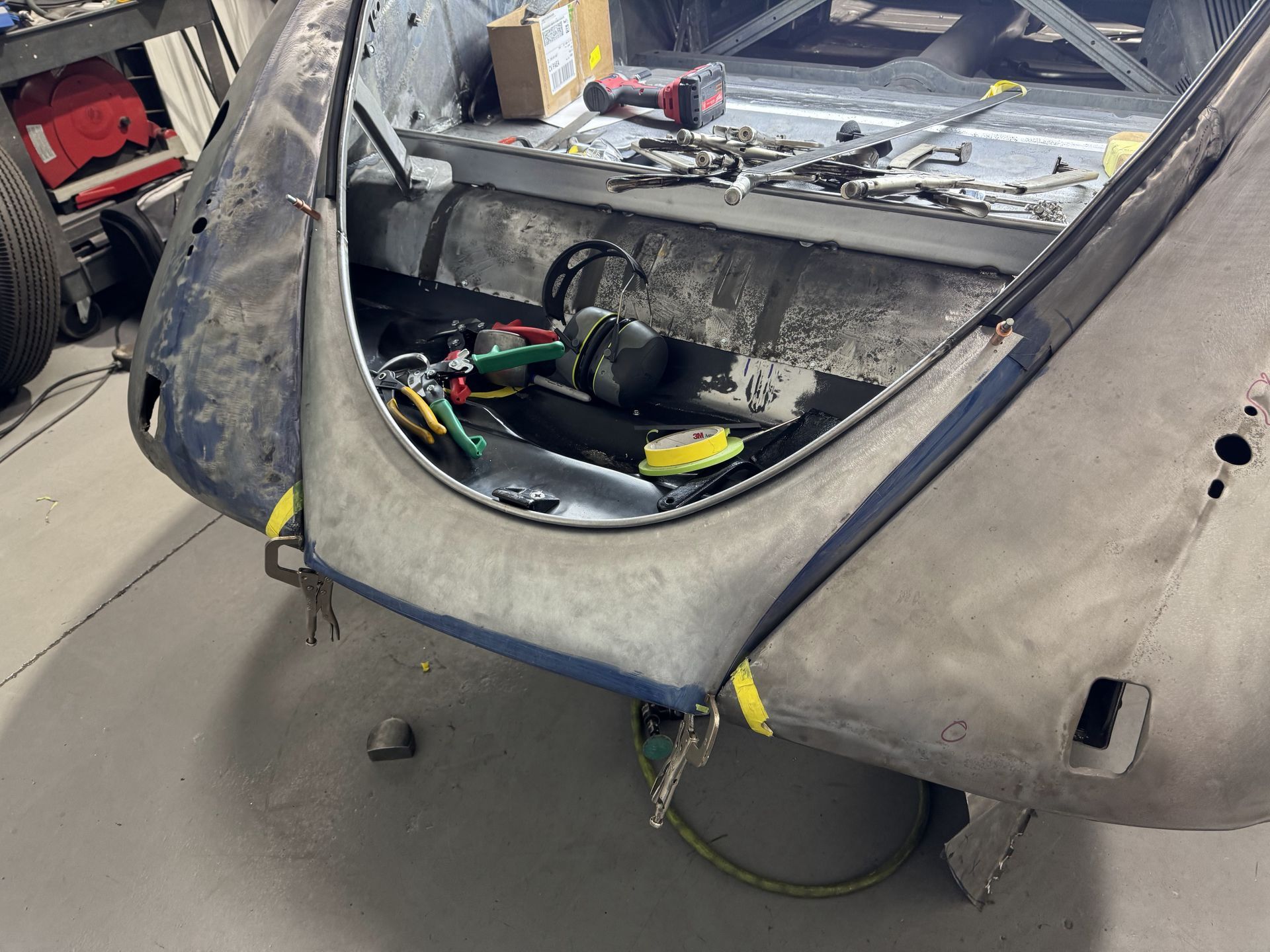 Open car trunk with exposed wiring and tools during repair work
