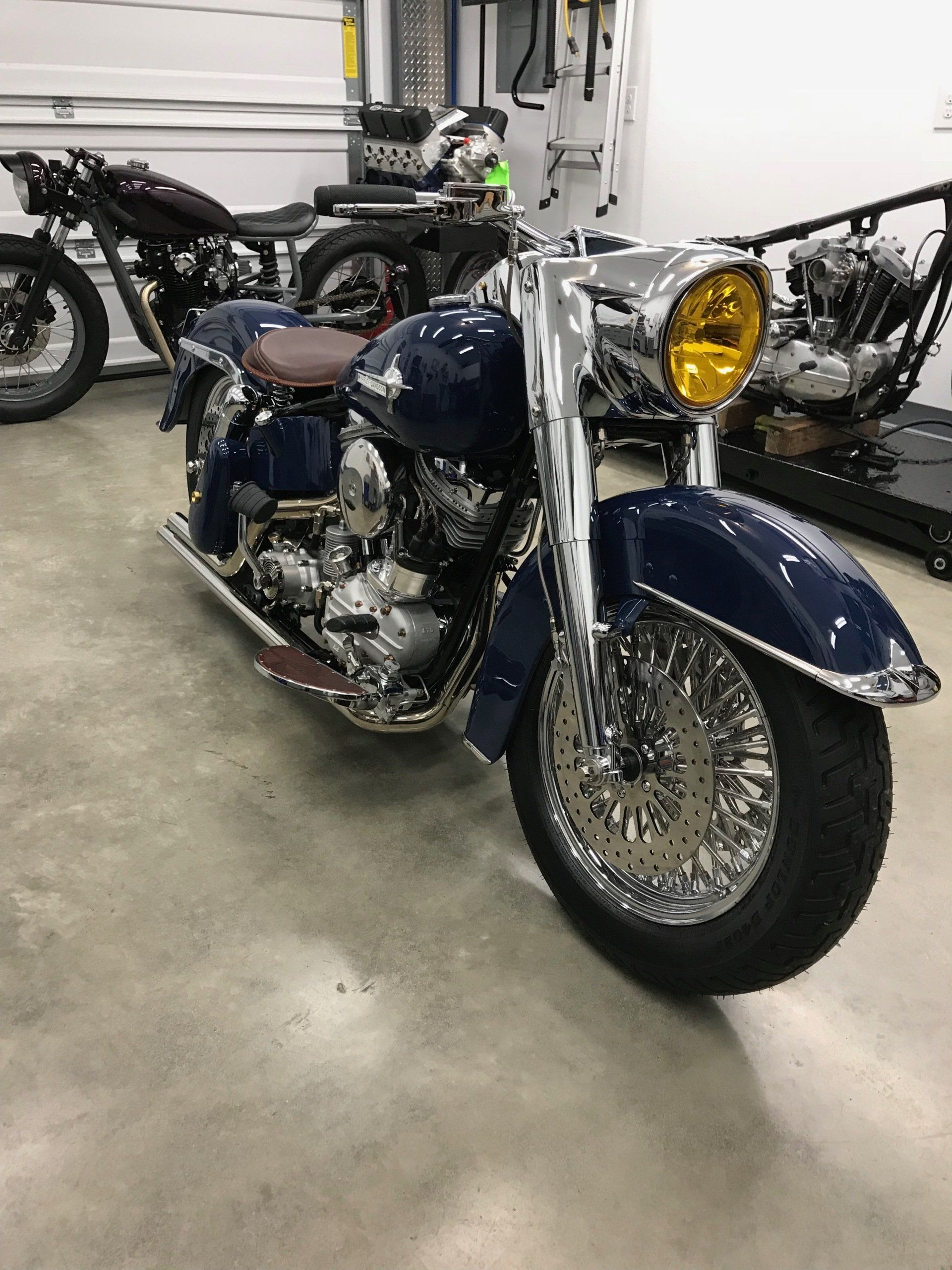 Blue vintage motorcycle with chrome details and yellow headlight in a garage
