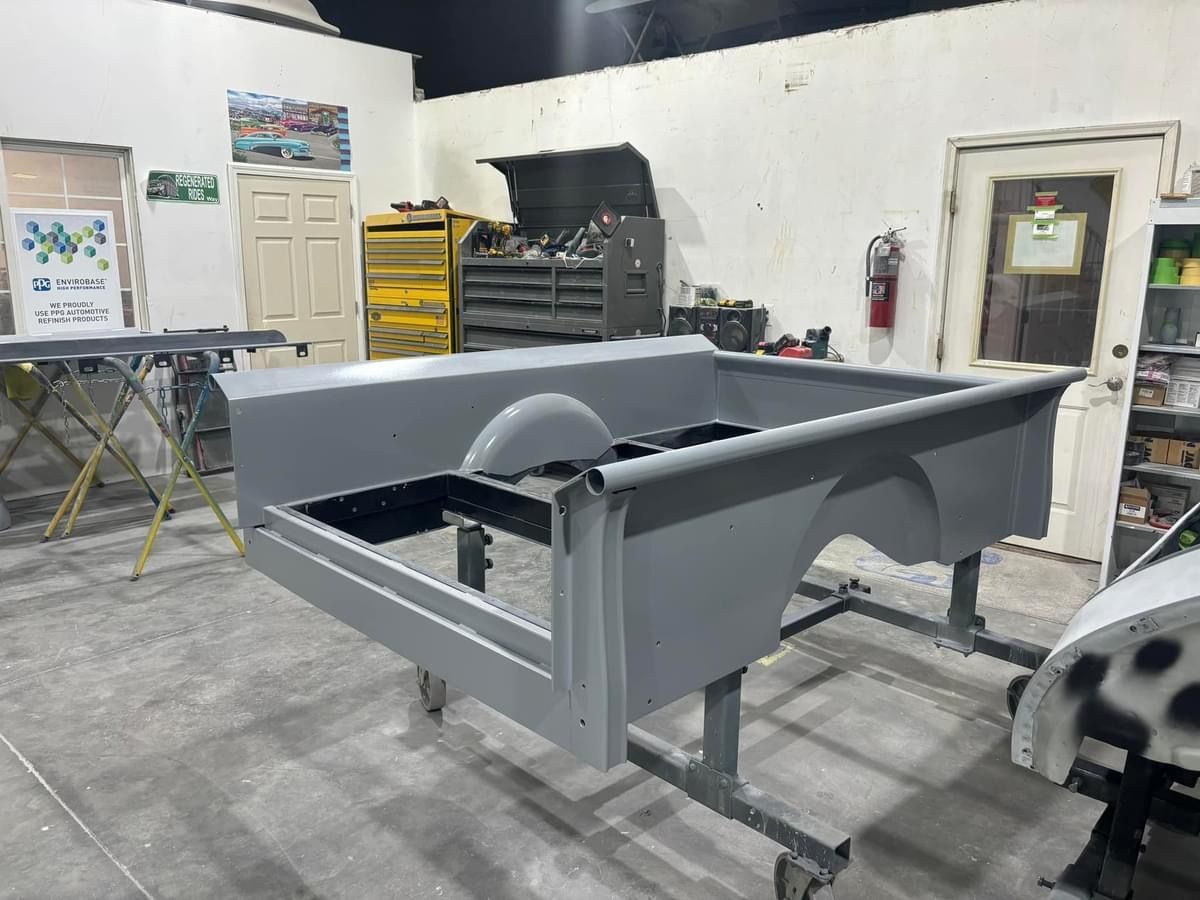 Gray metal machine frame in a workshop with tools, shelves, and a door in the background