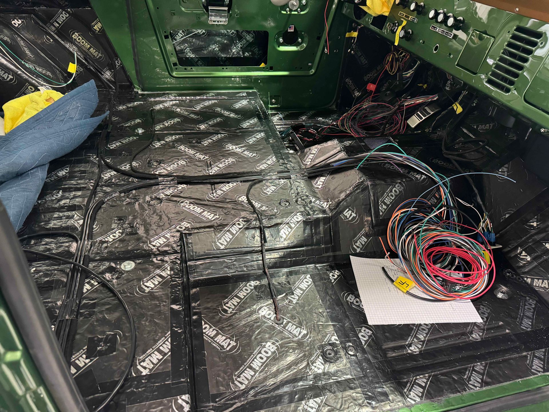 Green equipment bay with black floor lining and coiled multicolored cables on the right side