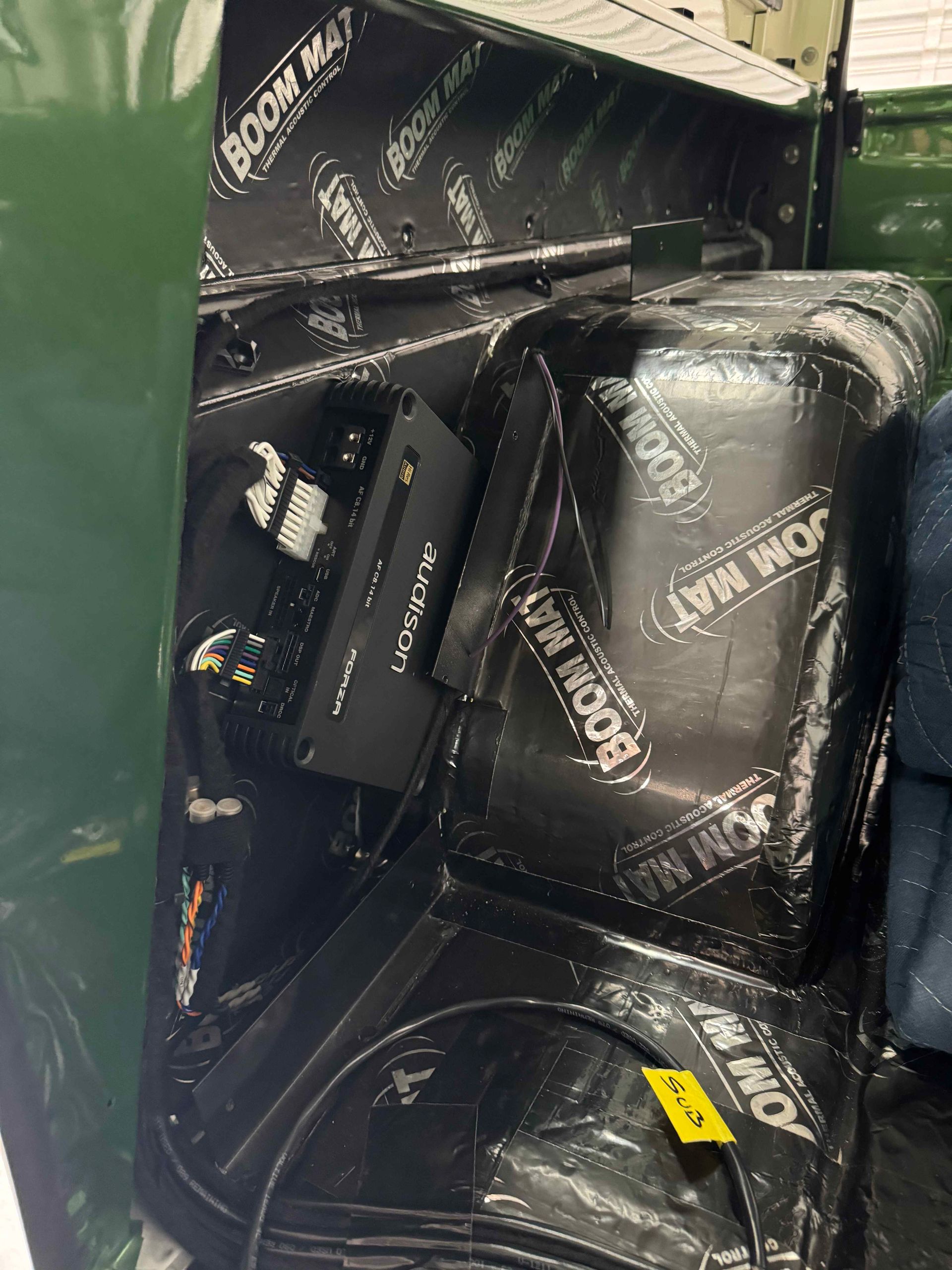 Black branded bags piled in a green bin, with a small yellow tag visible.