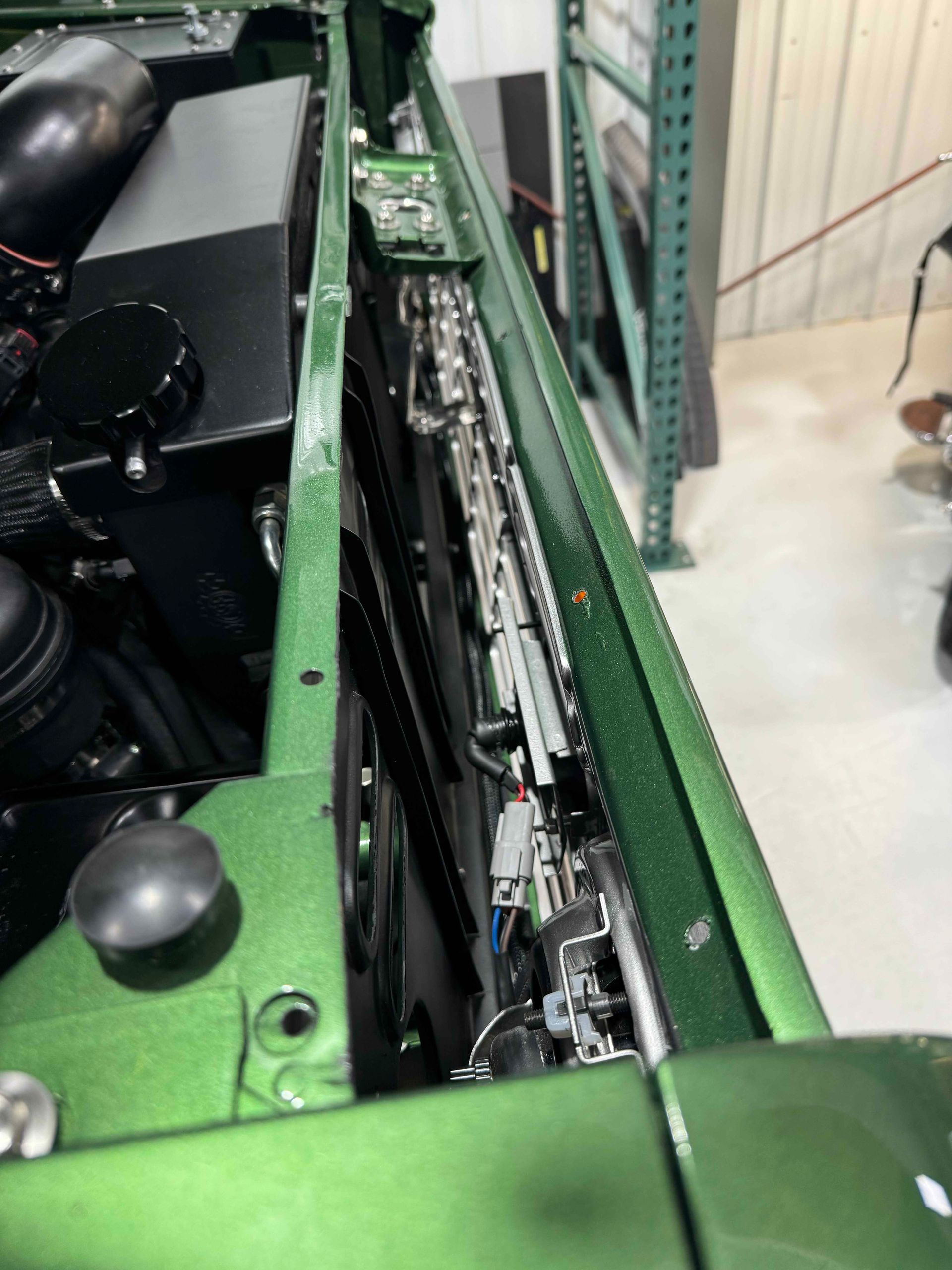 Close-up of green machinery with exposed internal components and wiring in a workshop.
