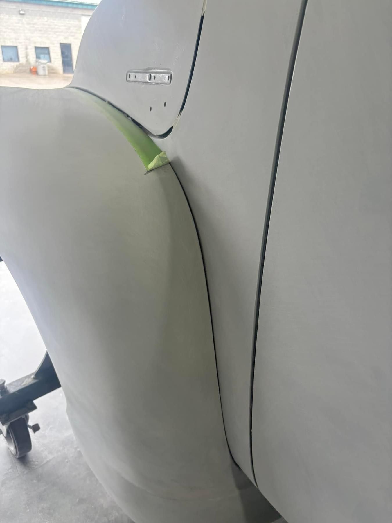 Close-up of a gray aircraft wing flap with a small green marking near the hinge.