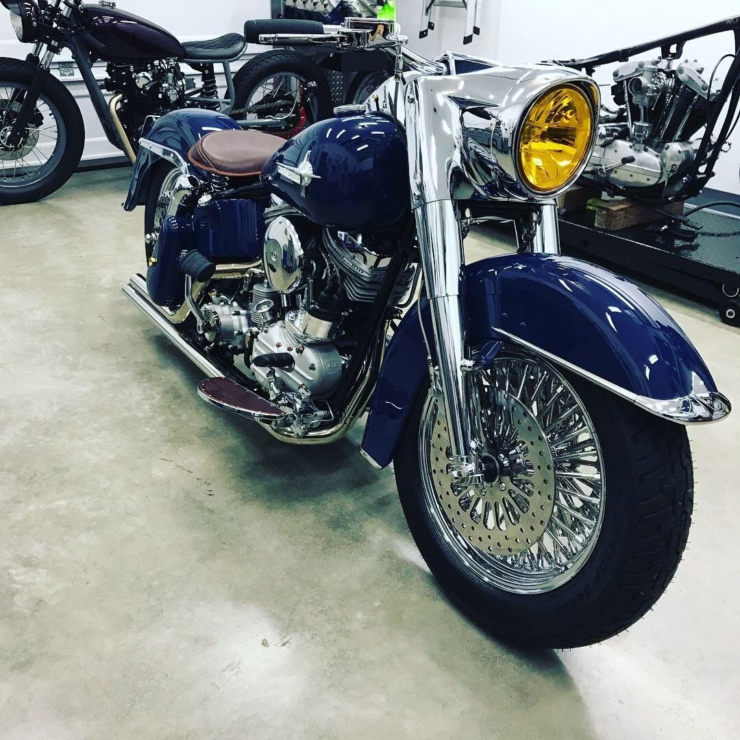 Blue vintage motorcycle with chrome details and yellow headlight in a showroom