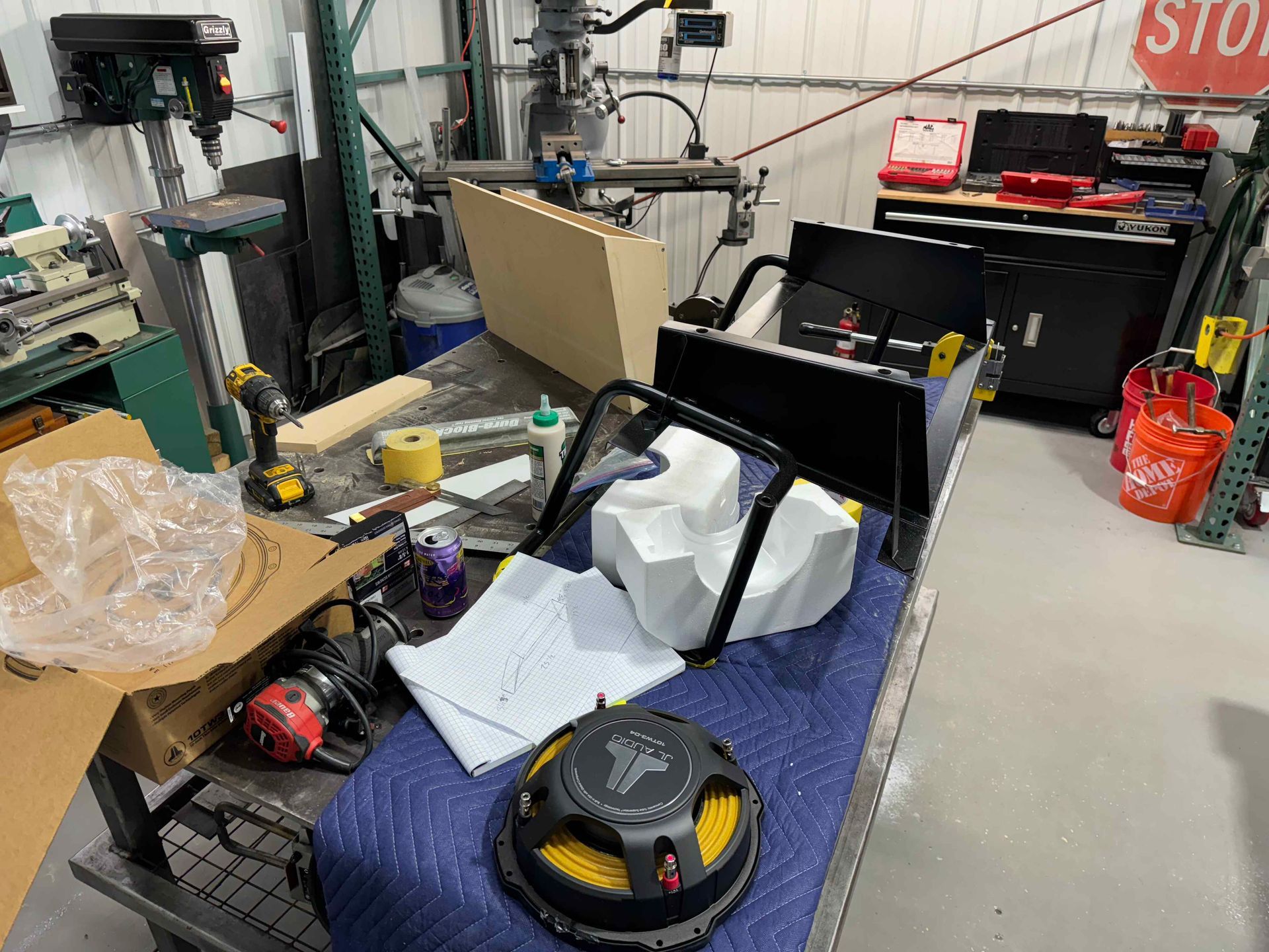 Messy workshop floor with a black wheeled cart, tools, and a vacuum cleaner.