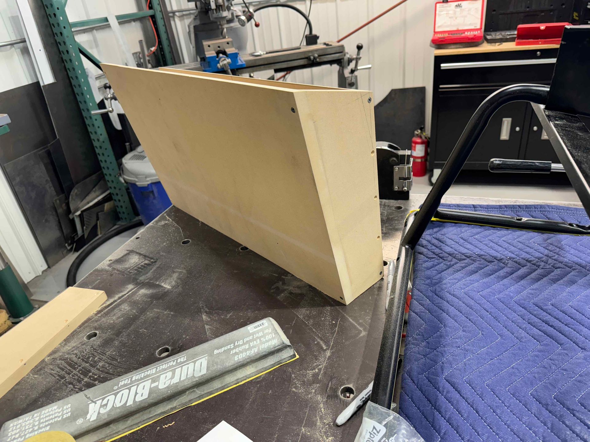 Workshop bench with a beige panel, metal ruler, and tools on a cluttered worktable