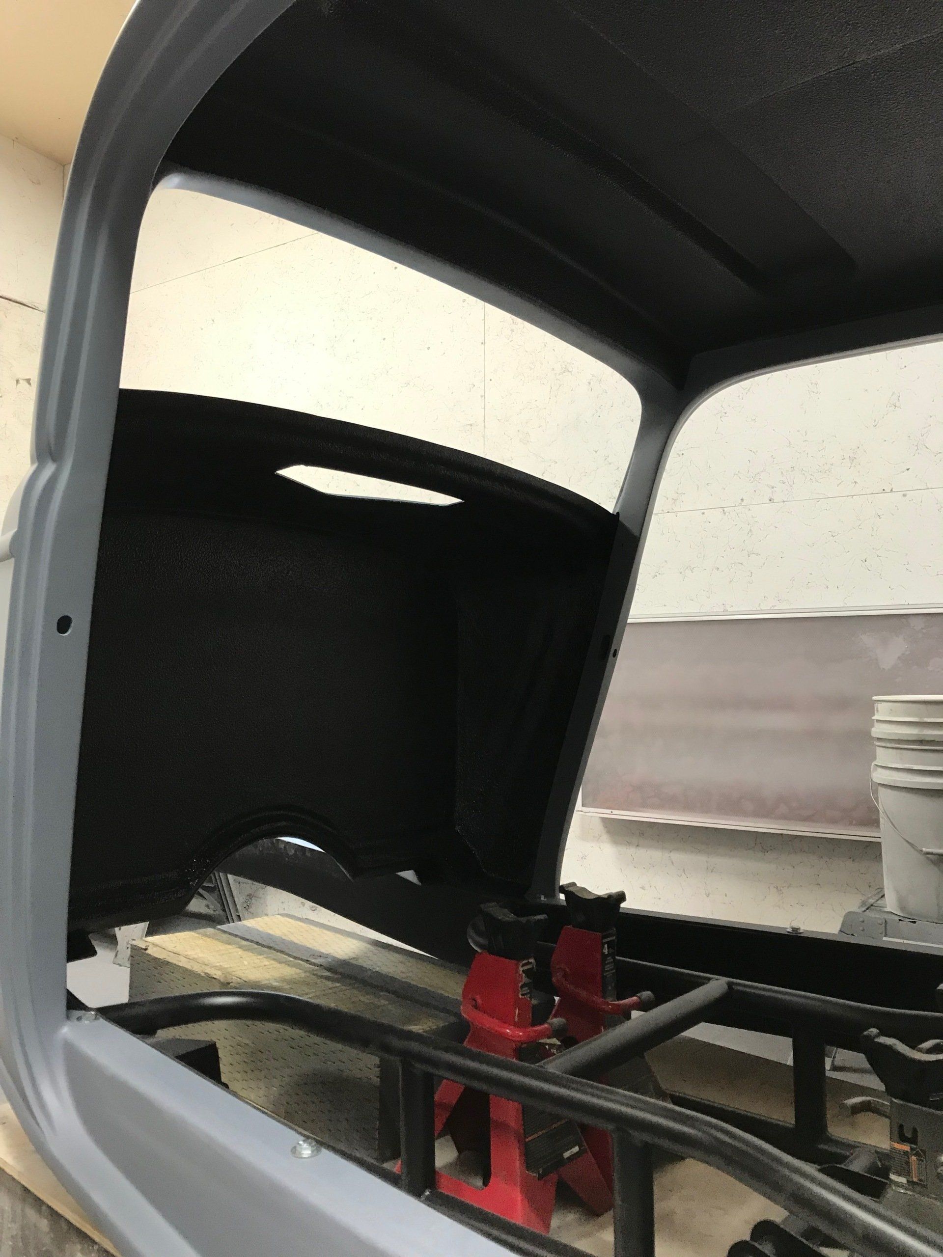 Inside a vehicle interior, showing a black-and-white cabin with red metal supports and wiring.