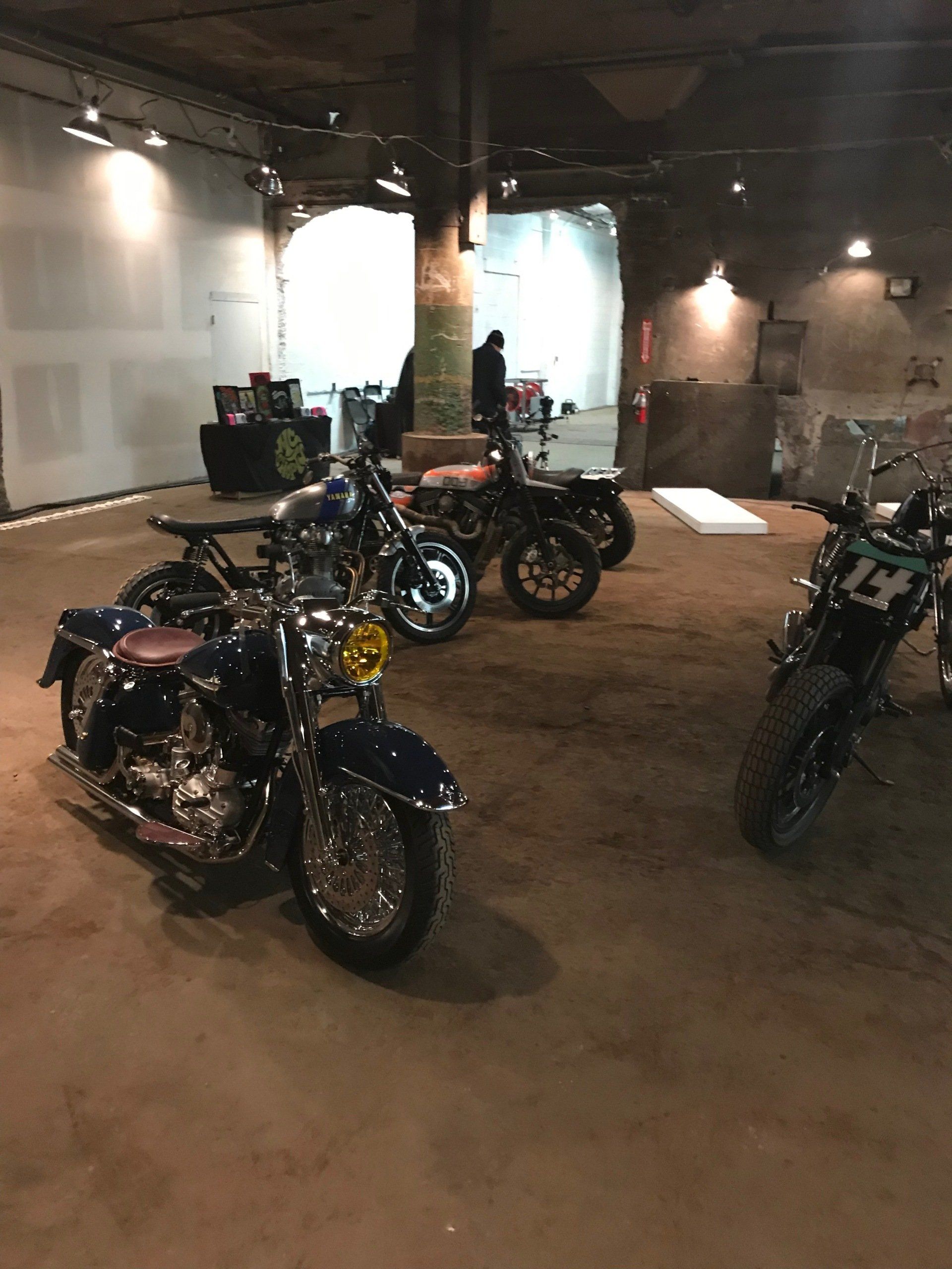 Motorcycles displayed in a dim indoor showroom with exposed brick and lights.
