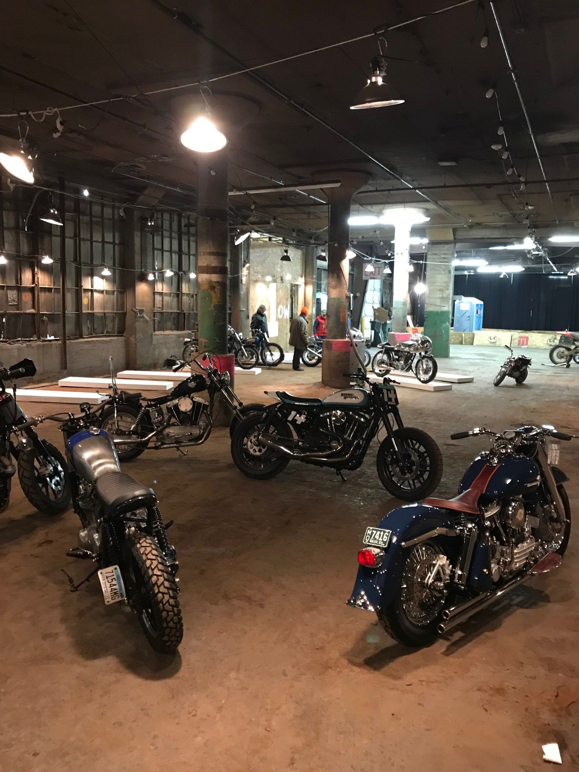 Motorcycles parked inside a dimly lit garage with a concrete floor and overhead lights