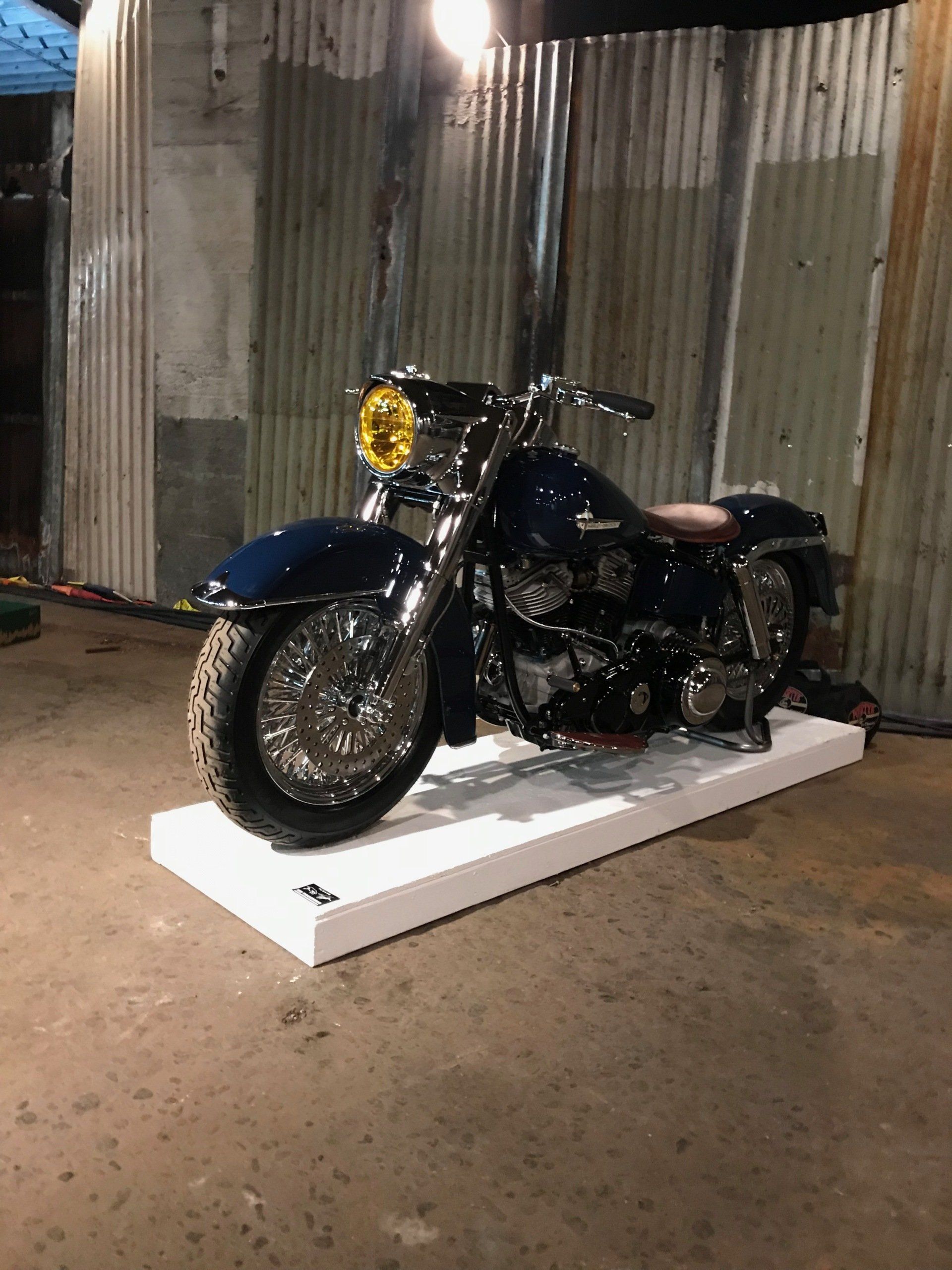 Black motorcycle on a white platform in a dim industrial garage